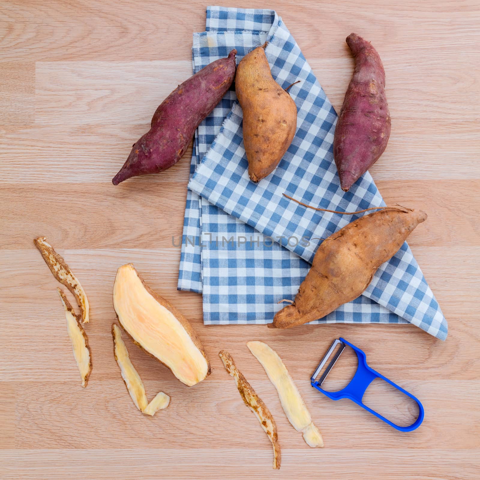 Peeled two varieties of sweet potatoes with peeler on rustic woo by kerdkanno