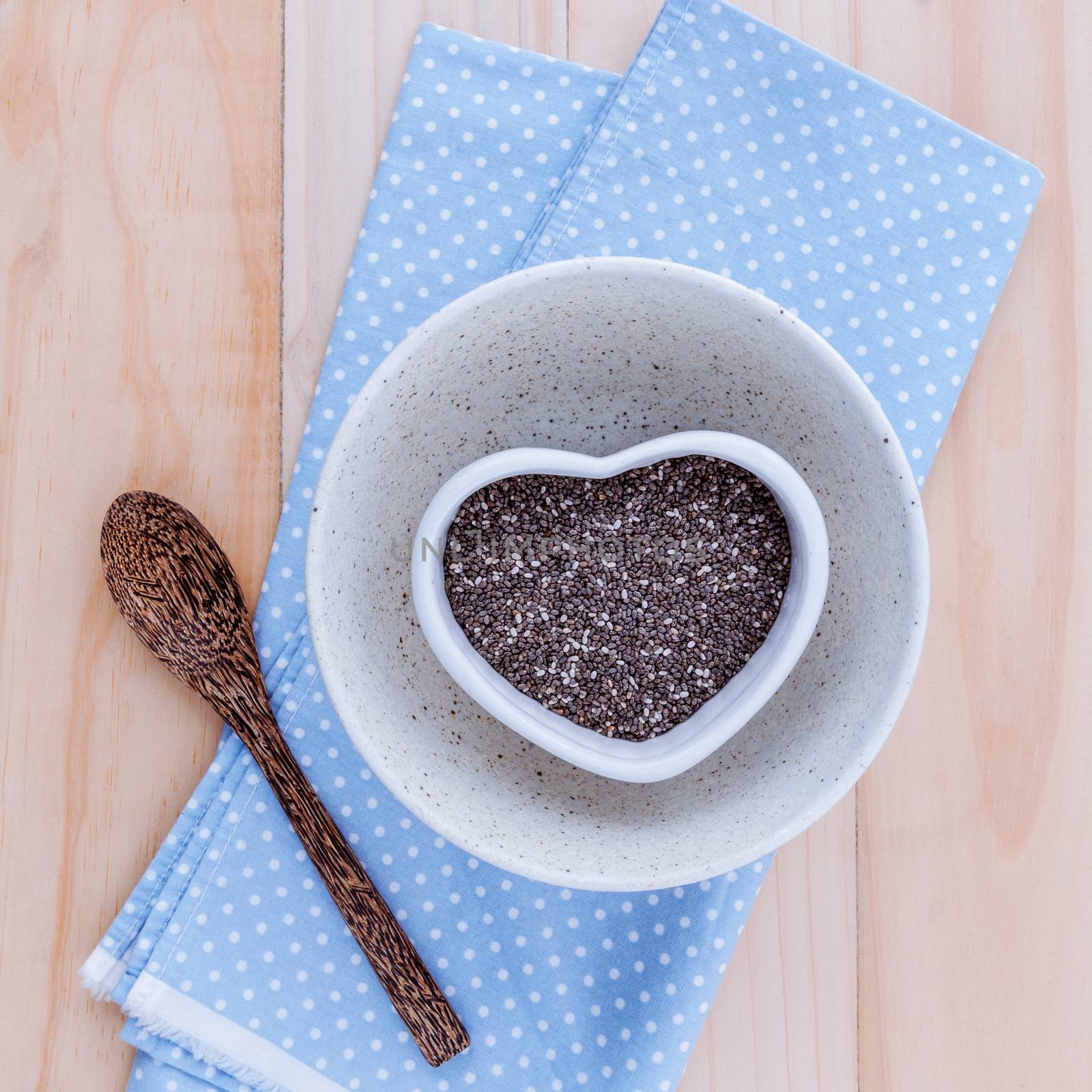 Alternative health care and dieting chia seeds in white bowl set up on rustic wooden background.