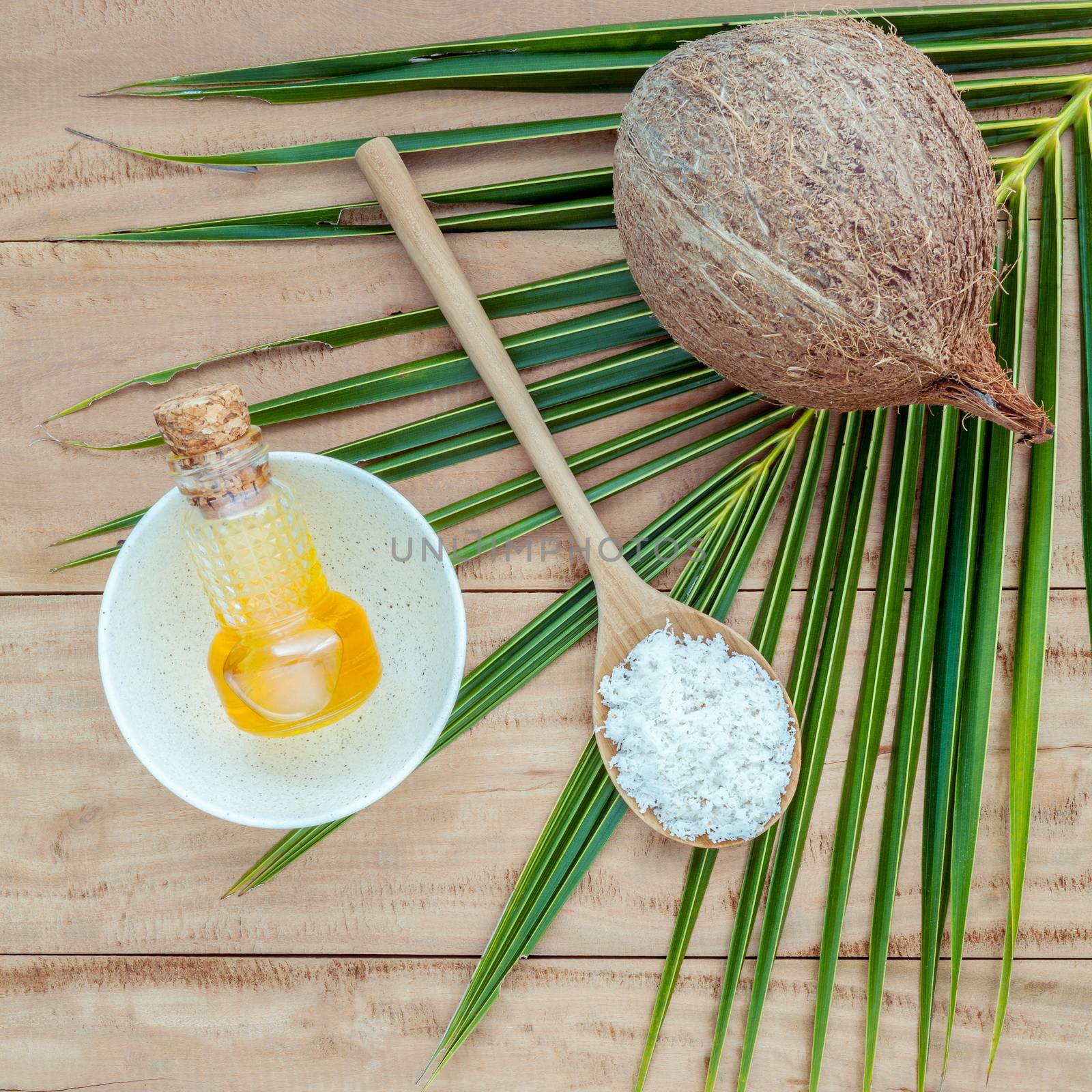 Coconut oil , coconut powder and coconut on coconut leaves set up on brown wooden background for alternative therapy.