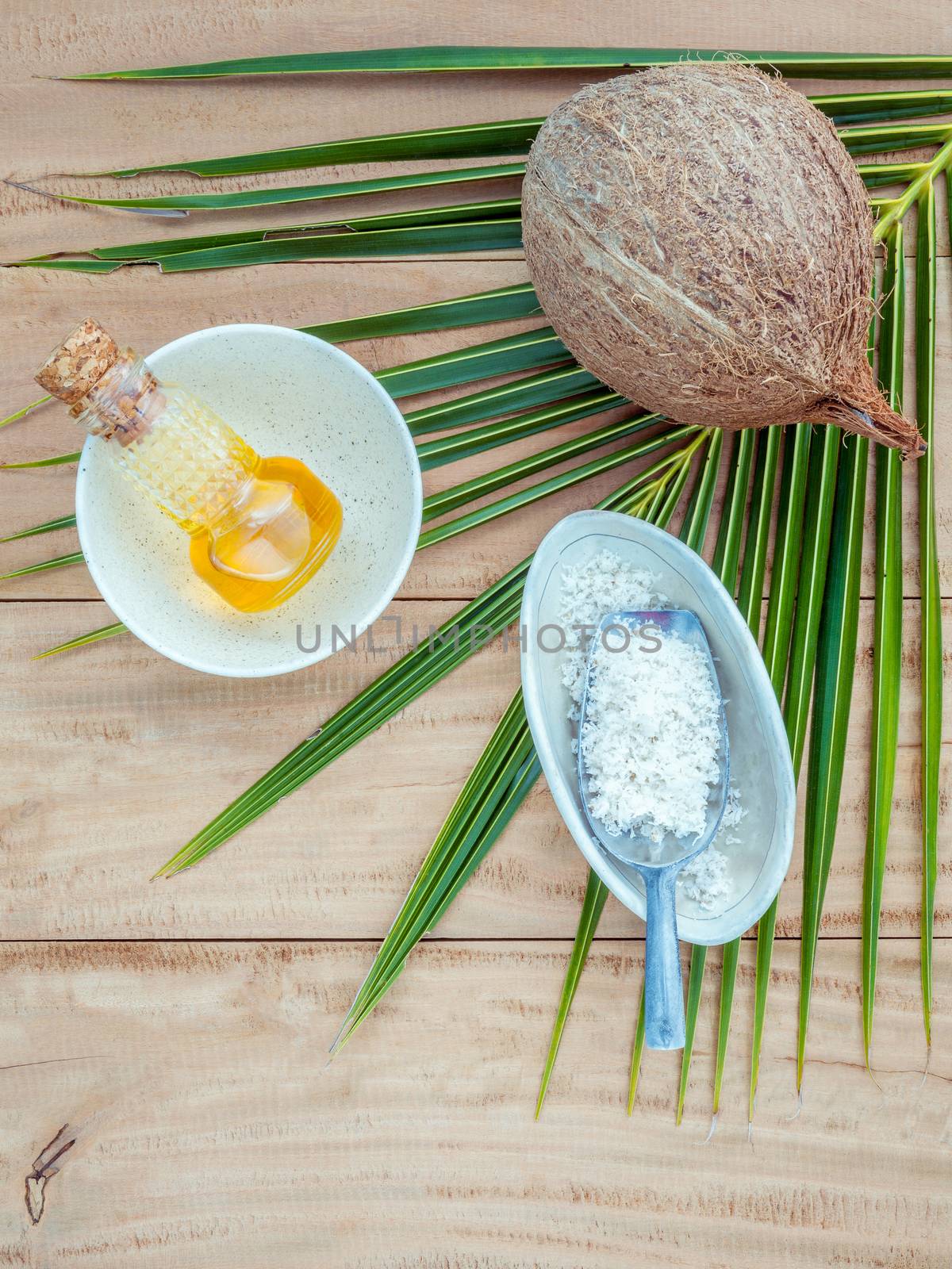 Coconut oil , coconut powder and coconut on coconut leaves set up on brown wooden background for alternative therapy.