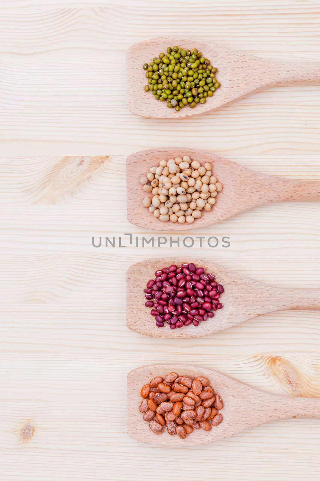 Assortment of beans and lentils in wooden spoon on wooden background.  soybean, mung bean , red bean and brown pinto beans .