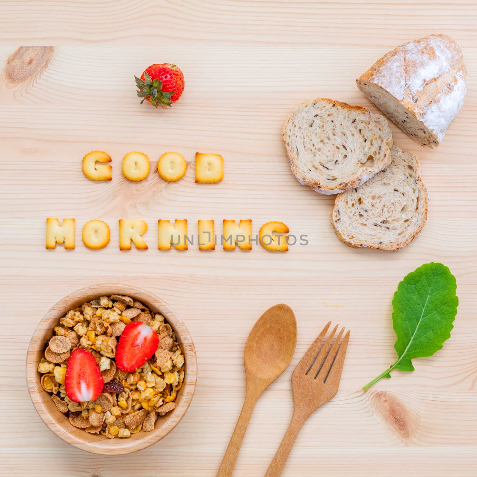 Good morning concept - Cereal in wooden bowl with strawberry and wooden spoon set up on wooden background.