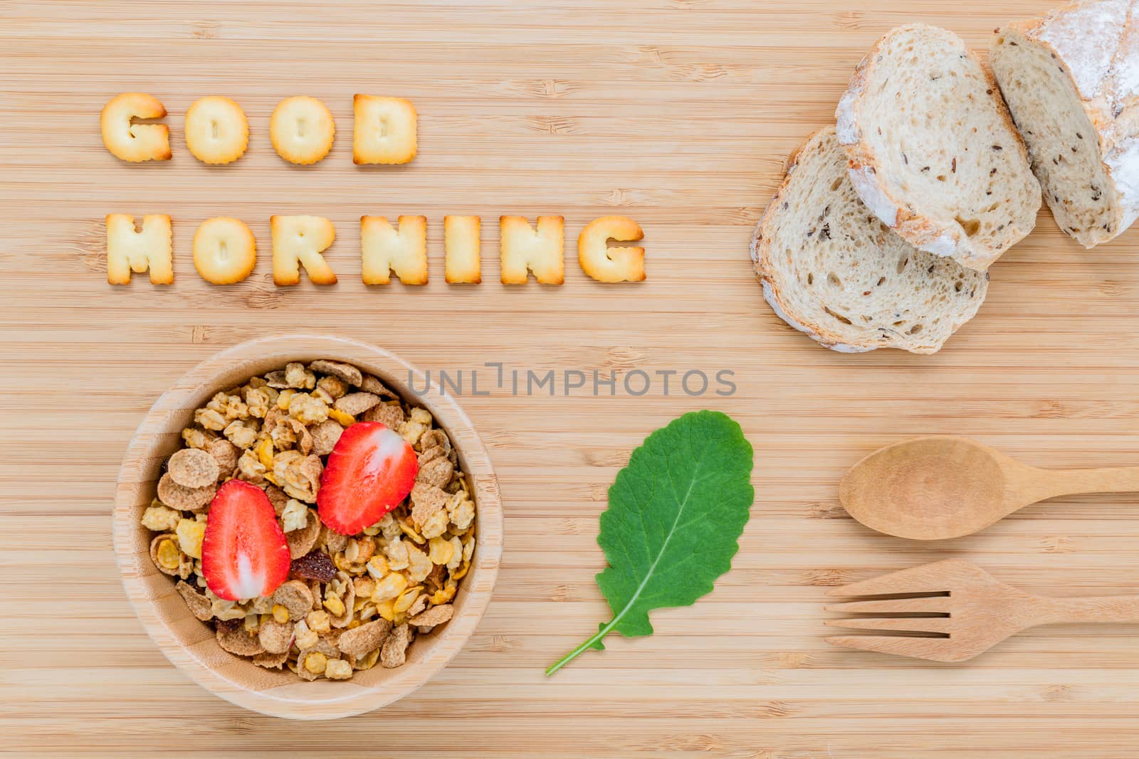 Good morning concept - Cereal in wooden bowl with strawberry and wooden spoon set up on wooden background.