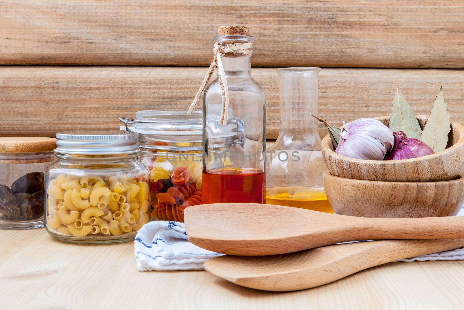 Italian food concept dried pasta with vegetables ,olive oil and spices herbs parsley , basil  and rosemary set up with white cheese on wooden background.