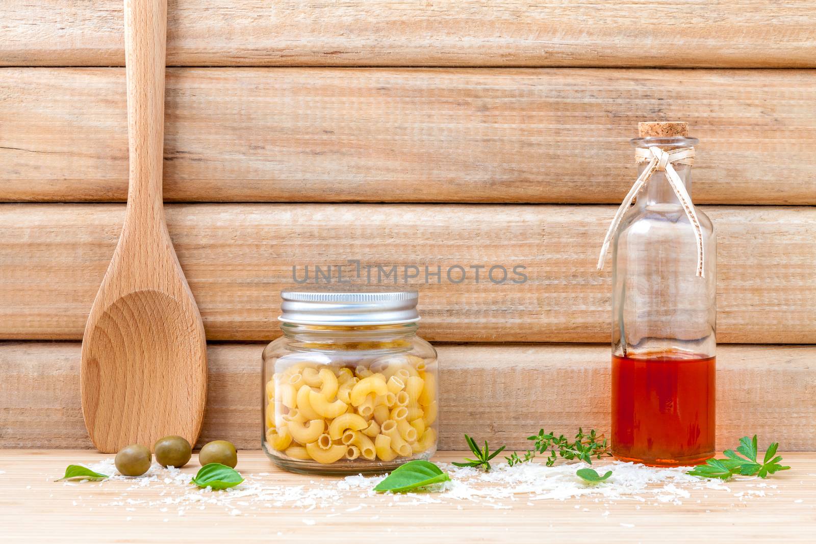 Italian food concept dried pasta with vegetables ,olive oil and spices herbs parsley , basil  and rosemary set up with white cheese on wooden background.