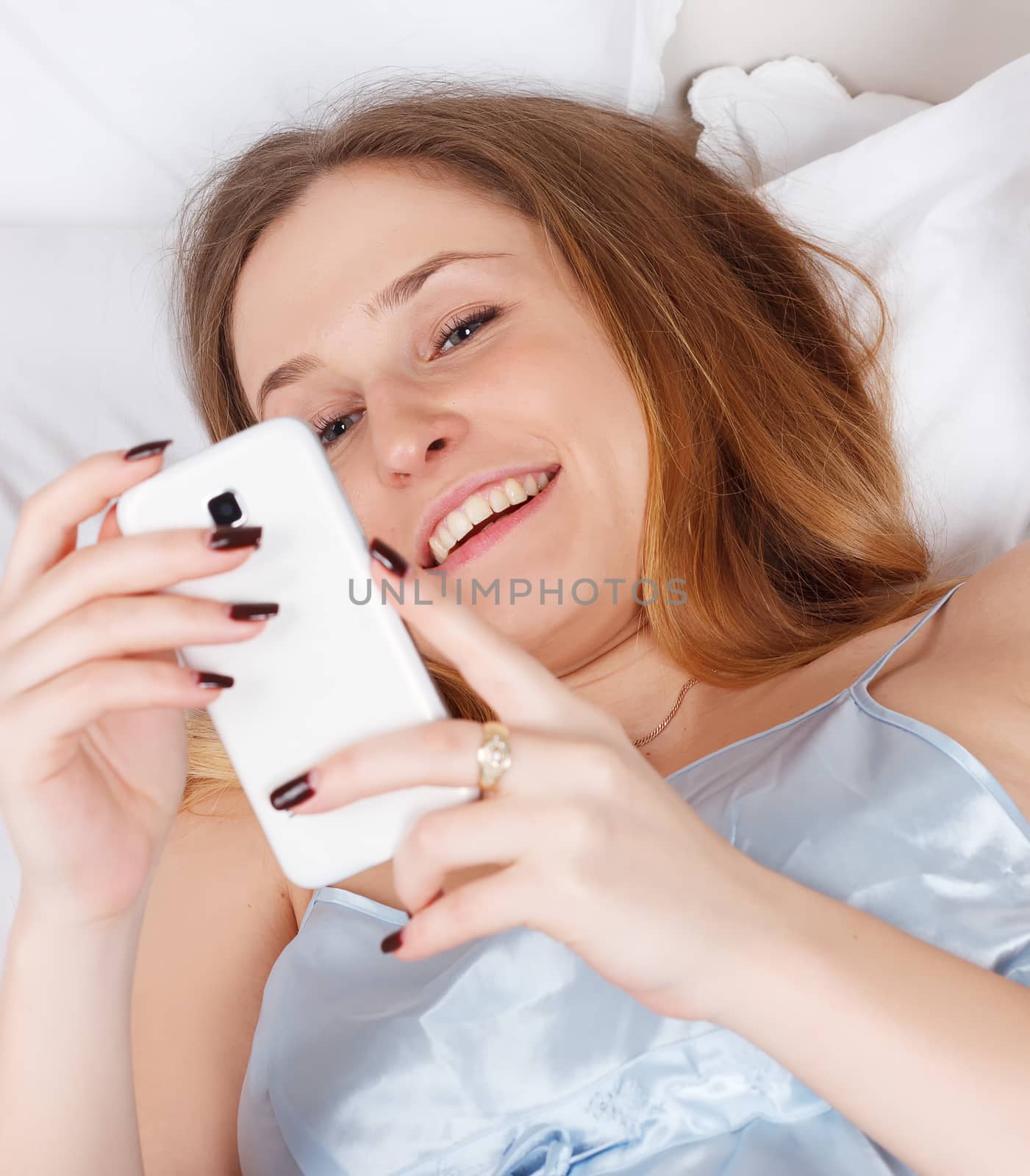 Portrait of a happy woman in her lovely bedroom texting