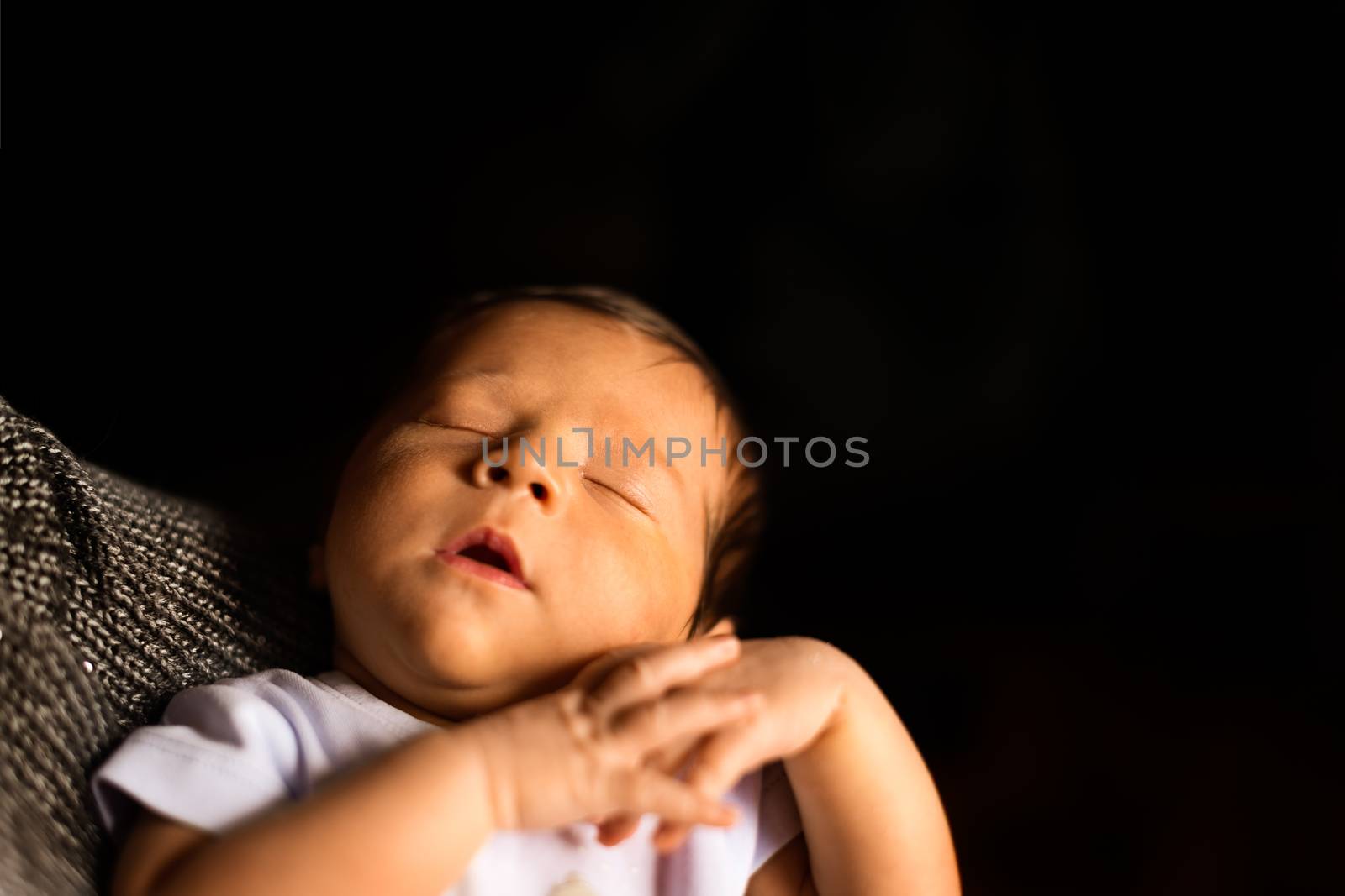 A Newborn Sleeps in his Father's Arms with black background for copyspace.