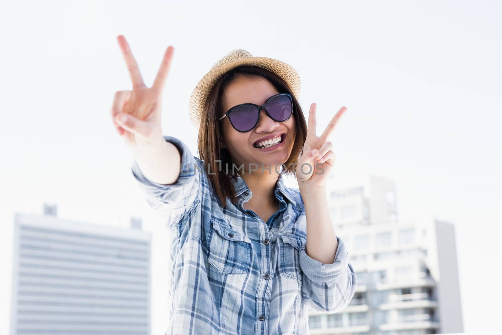 Happy young woman doing a v sign by Wavebreakmedia