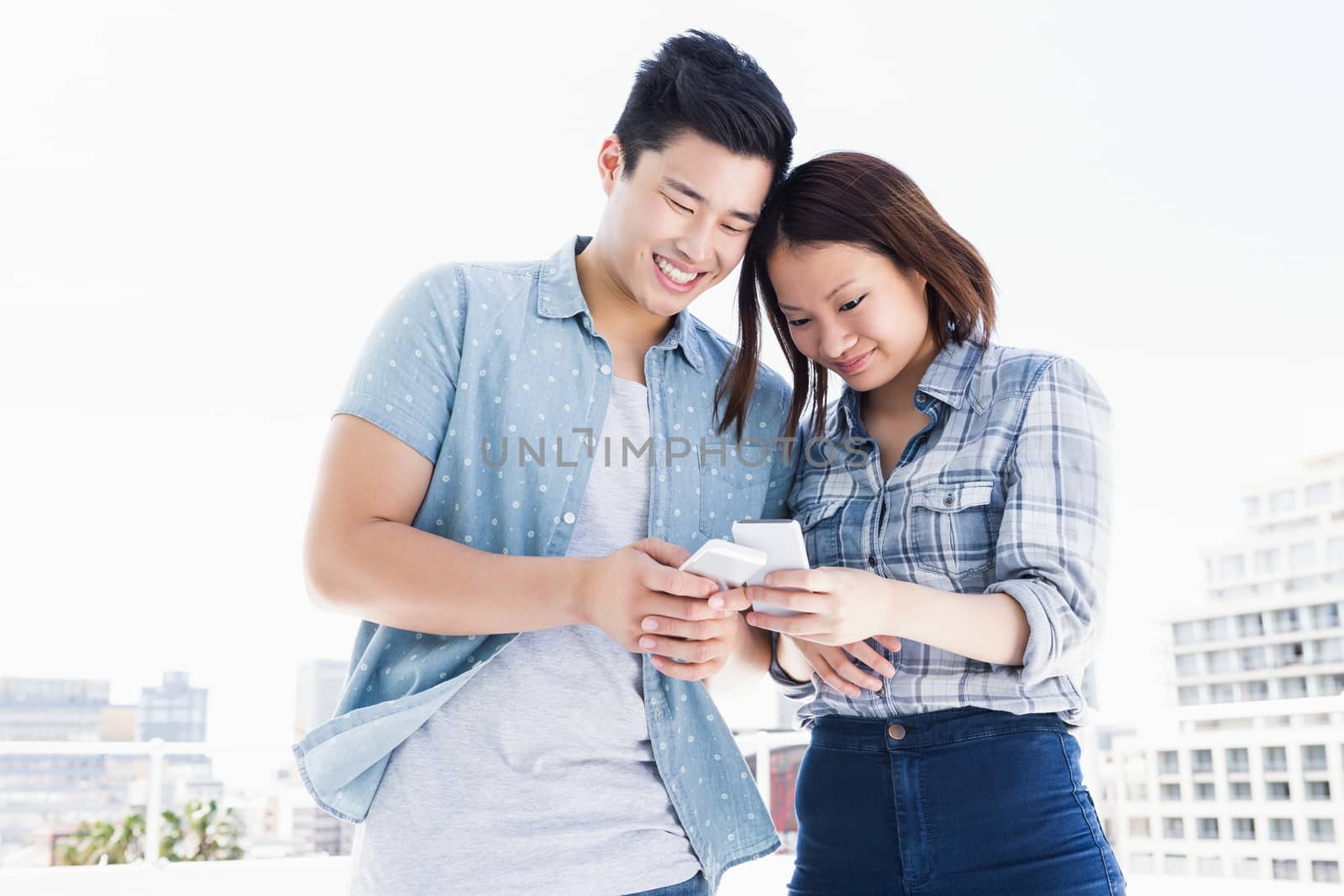 Happy young couple using mobile phone by Wavebreakmedia