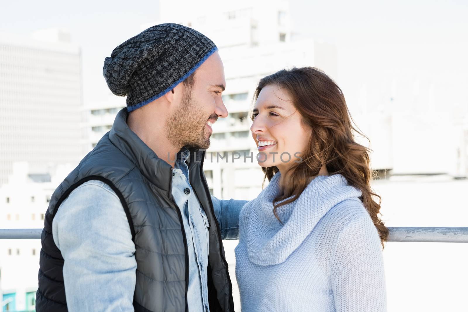 Happy young couple standing face to face and smiling outdoors