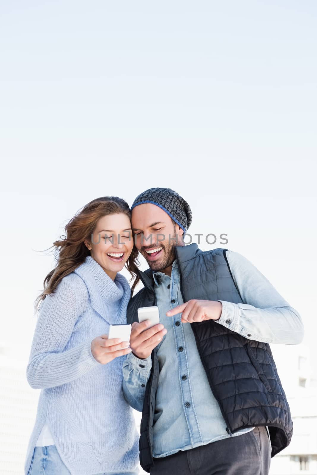 Happy young couple using mobile phone outdoors