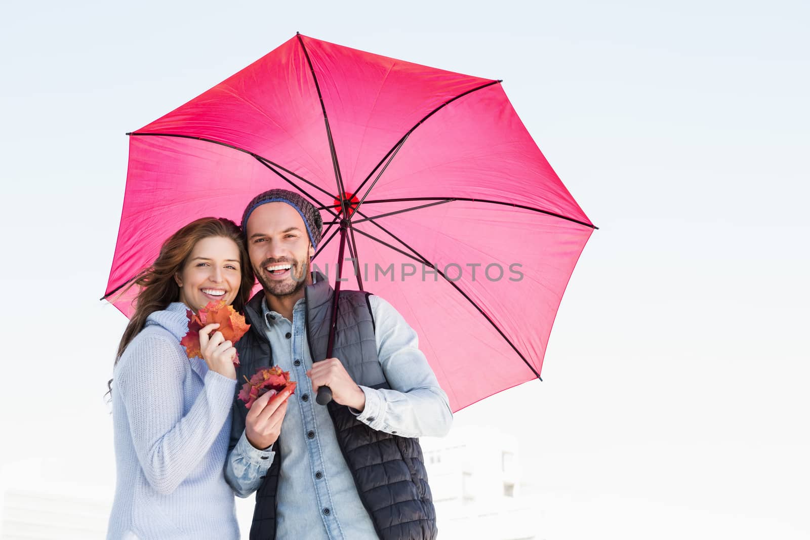 Happy young couple holding umbrella by Wavebreakmedia