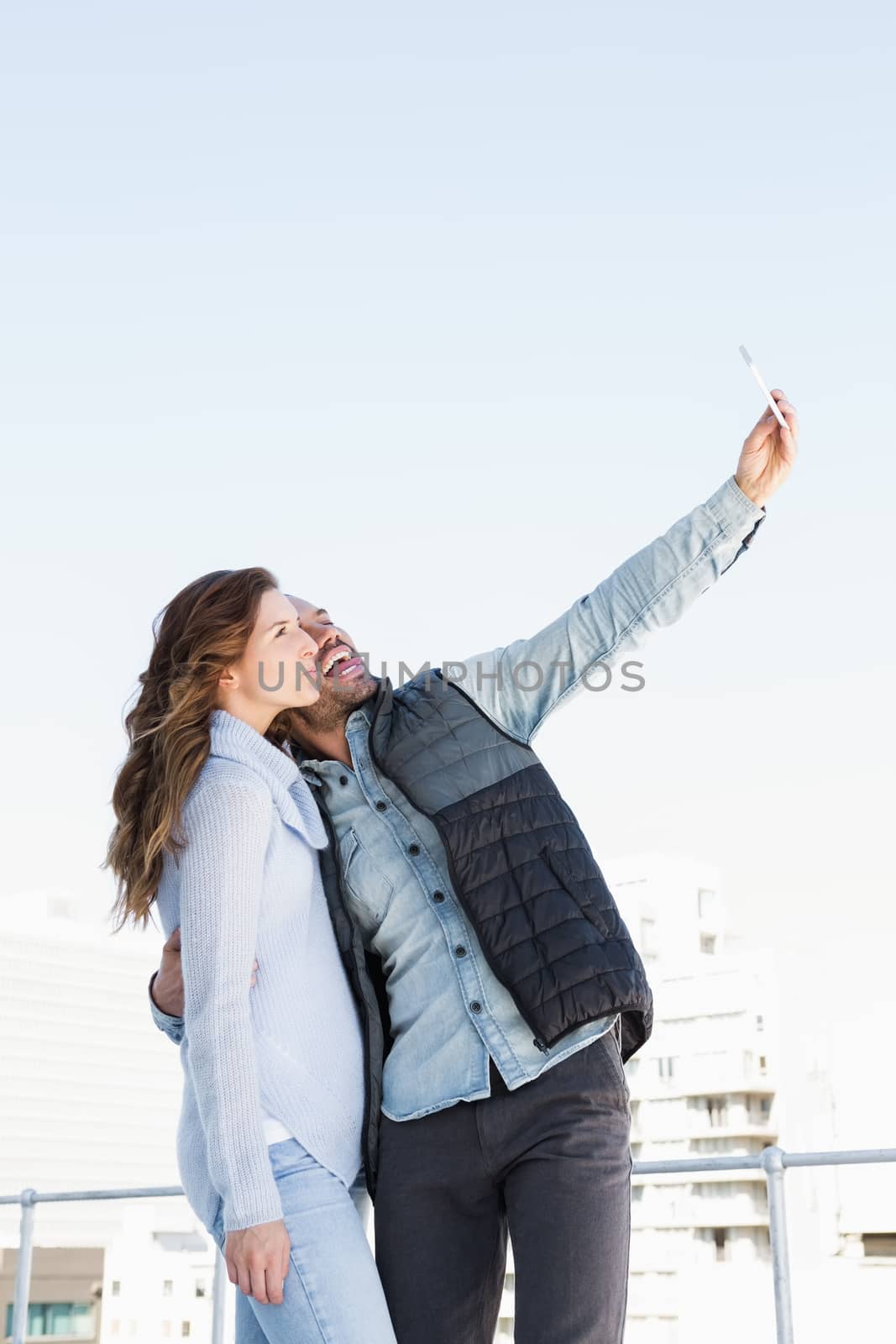 Young happy couple taking selfie on mobile phone outdoors