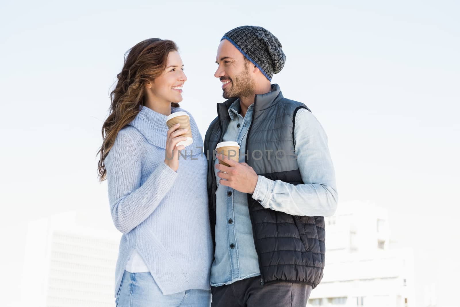 Happy young couple holding disposable coffee cup outdoors