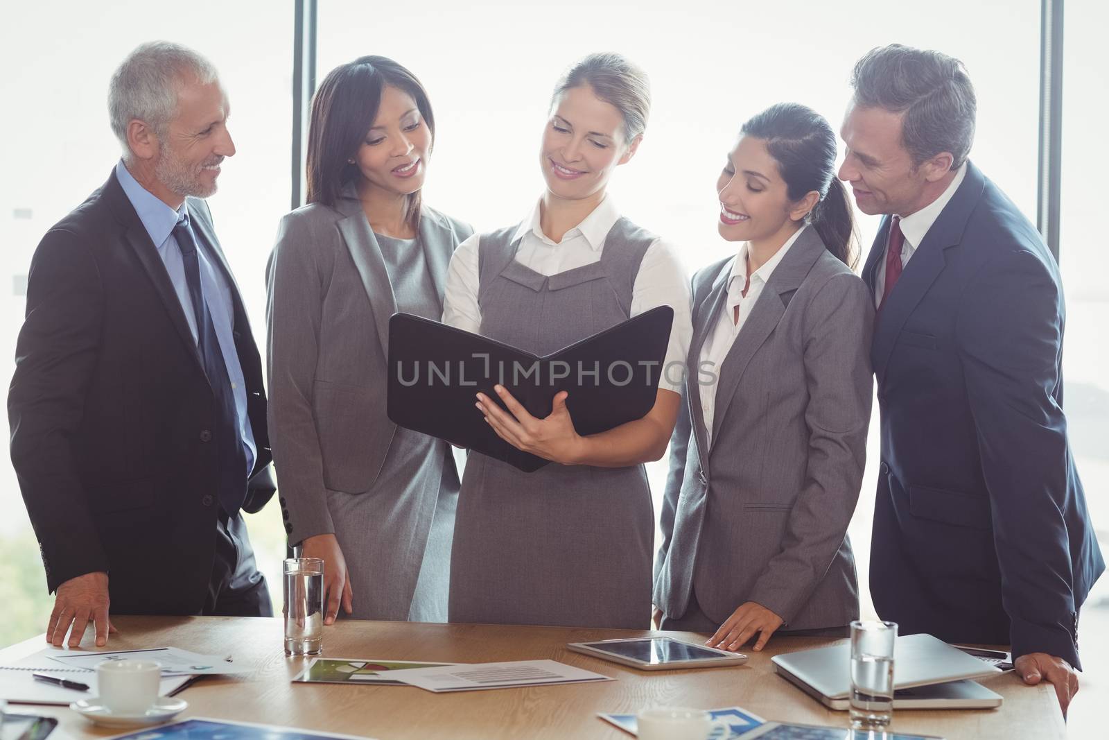 Businesswoman looking at organizer and interacting with team in office