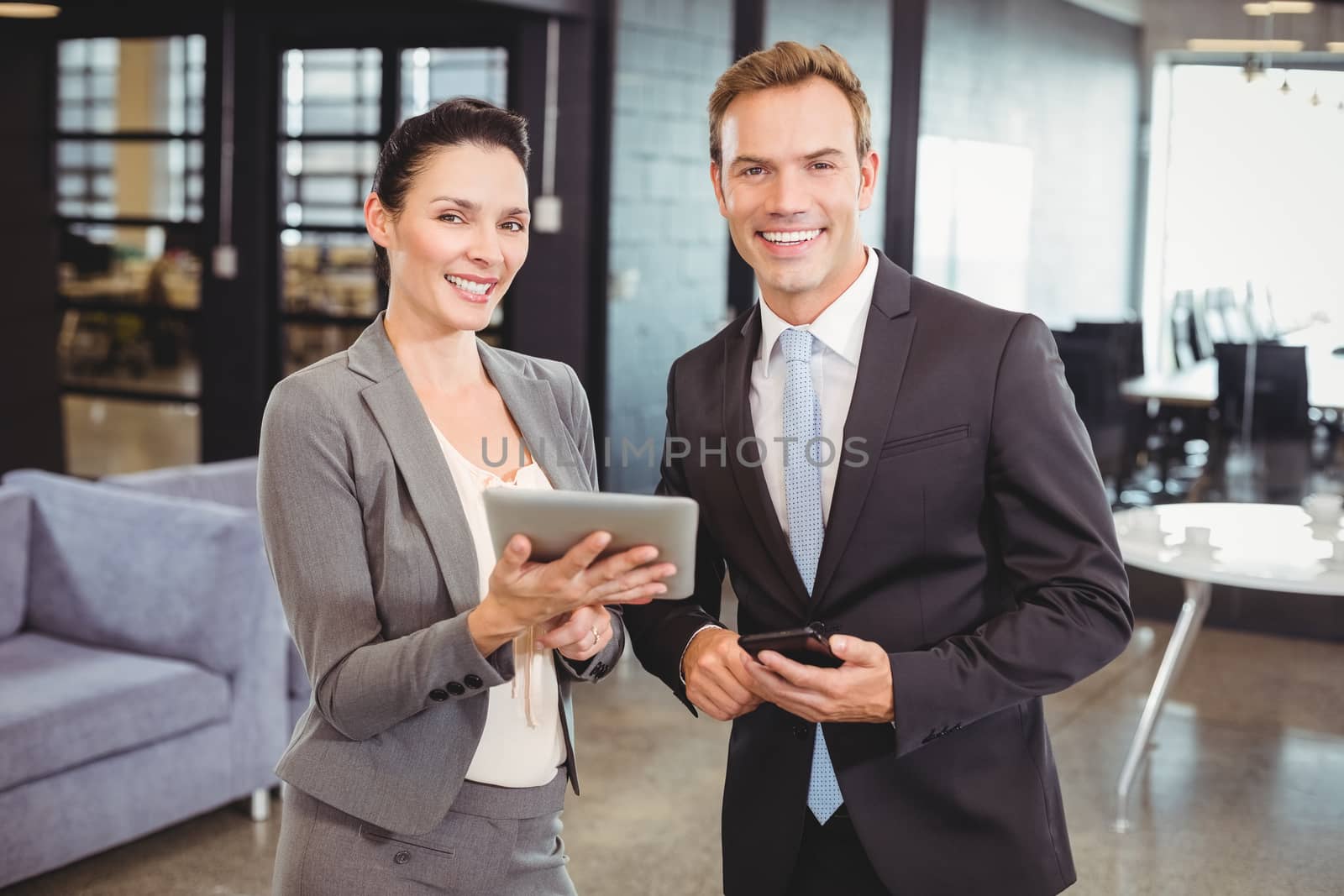 Portrait of happy businessman and businesswoman with digital tablet and mobile phone