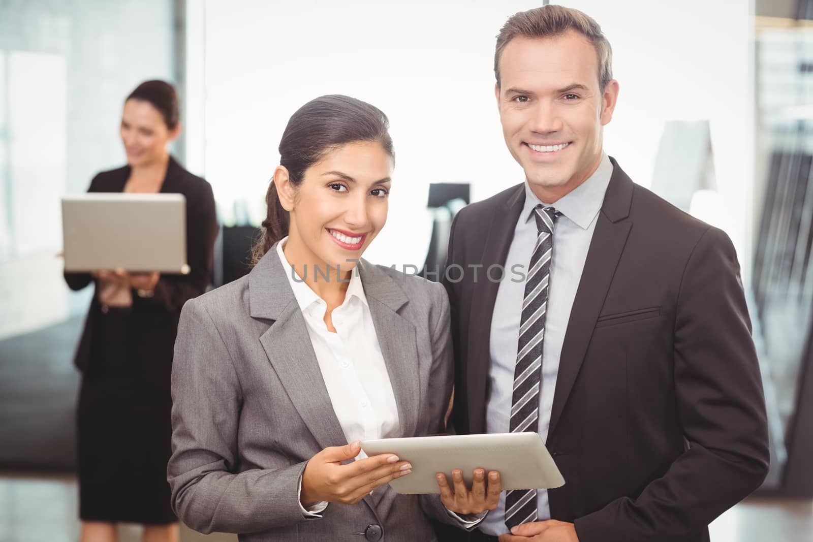 Portrait of businessman and businesswoman holding digital tablet at office