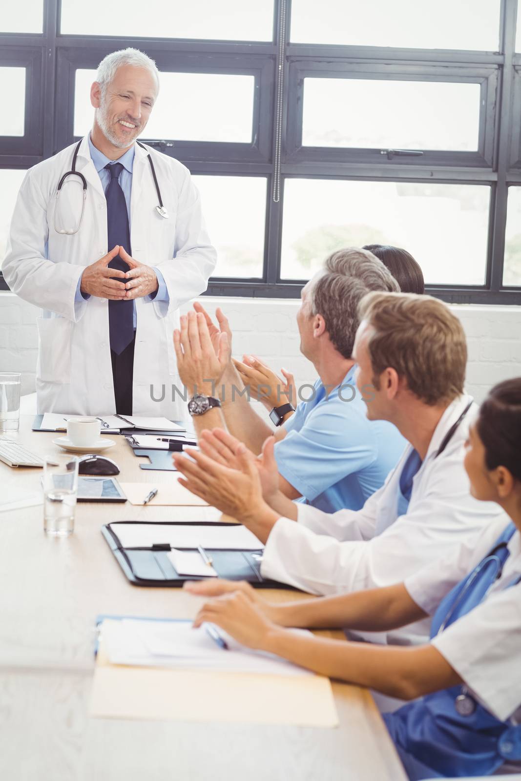 Doctors applauding a fellow doctor for his speech in conference room