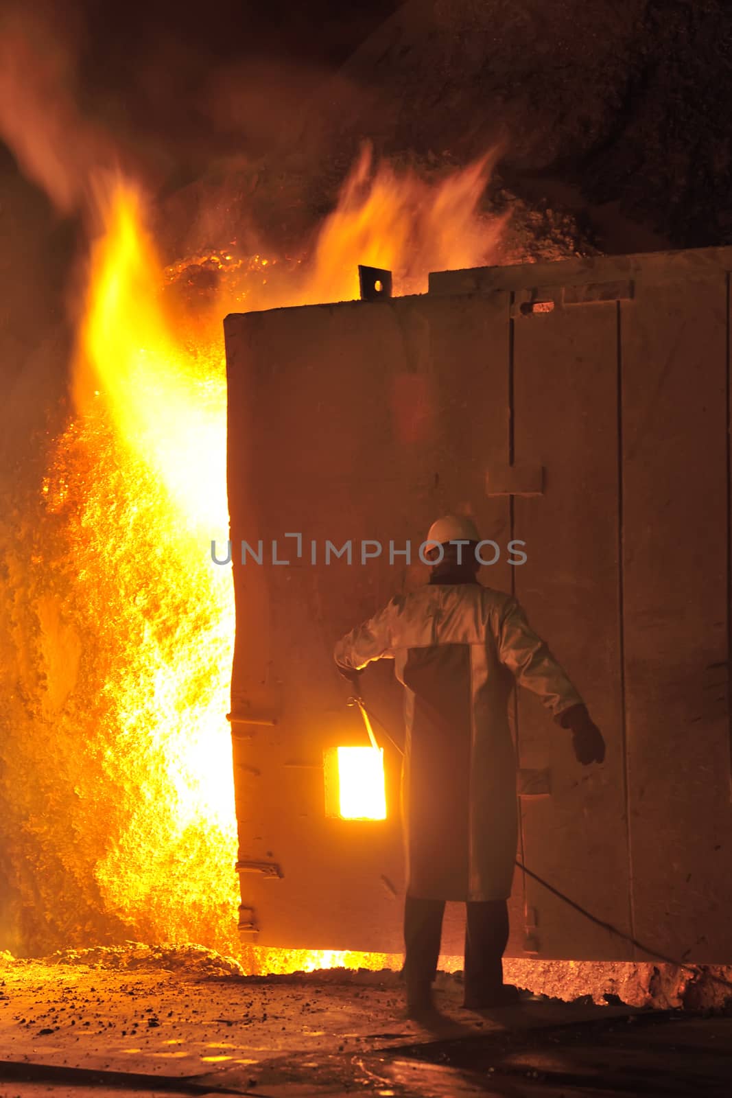 steel worker takes a sample from oven in steel plant