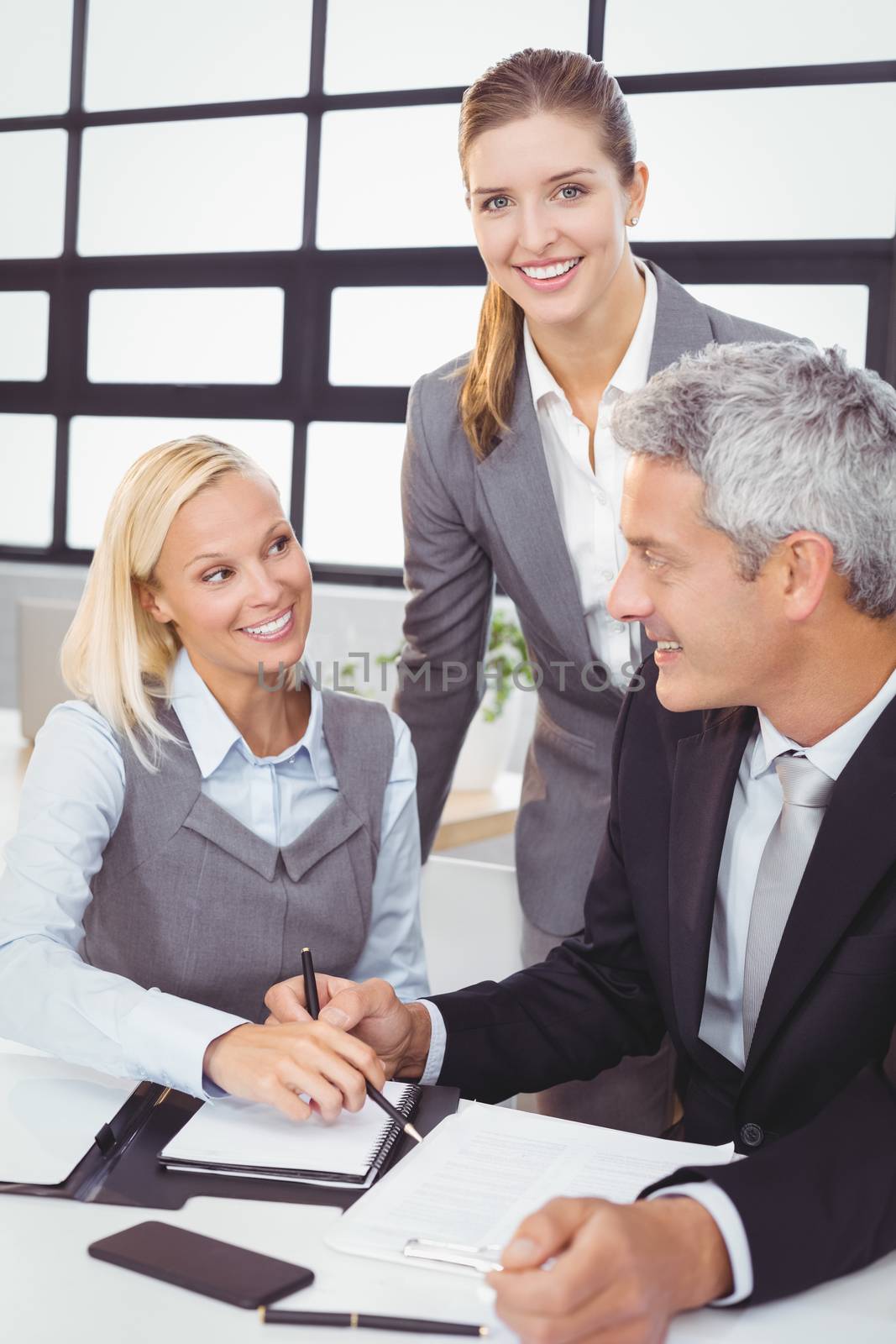 Happy business people with documents at desk in meeting room