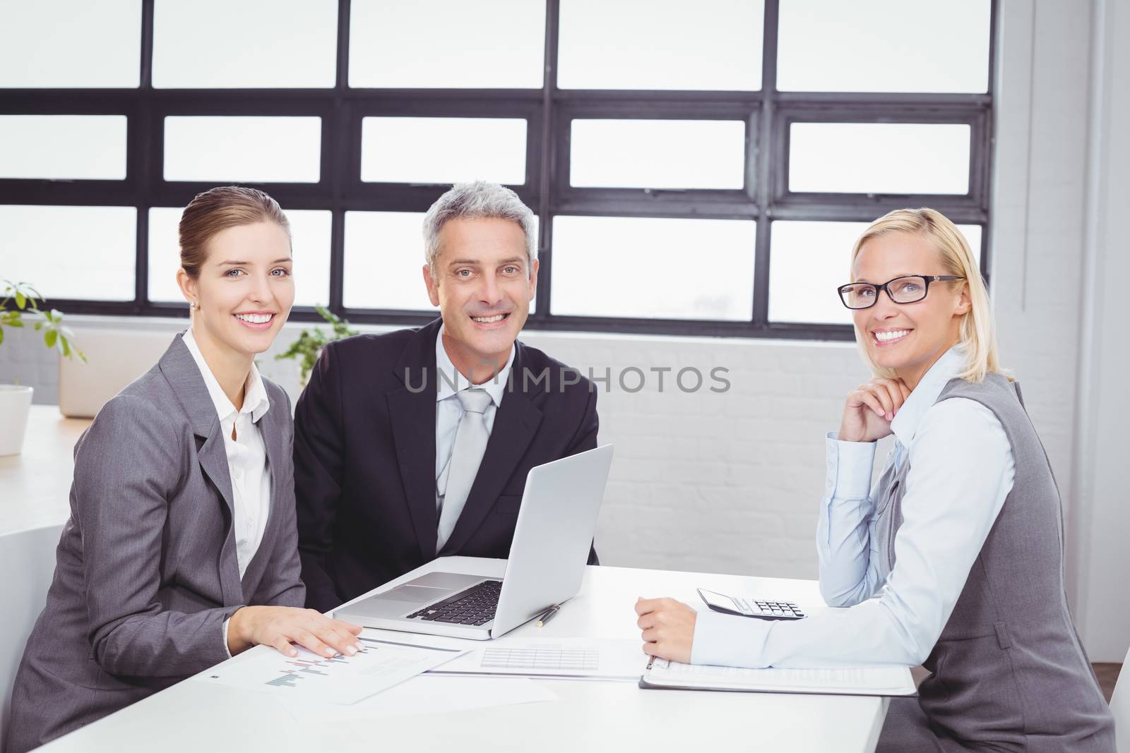 Portrait of happy business people with client in meeting room