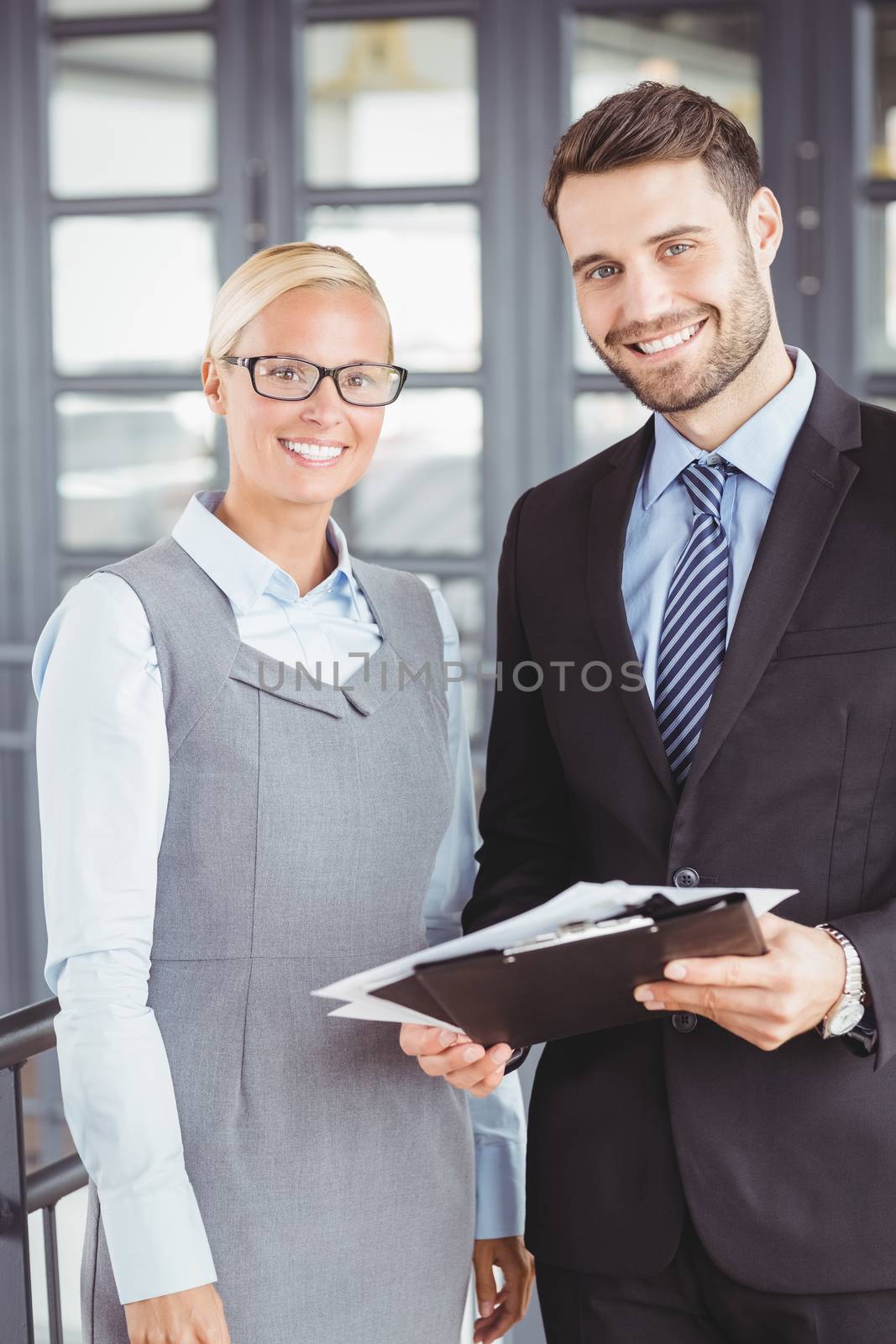 Portrait of happy business people with documents standing in office