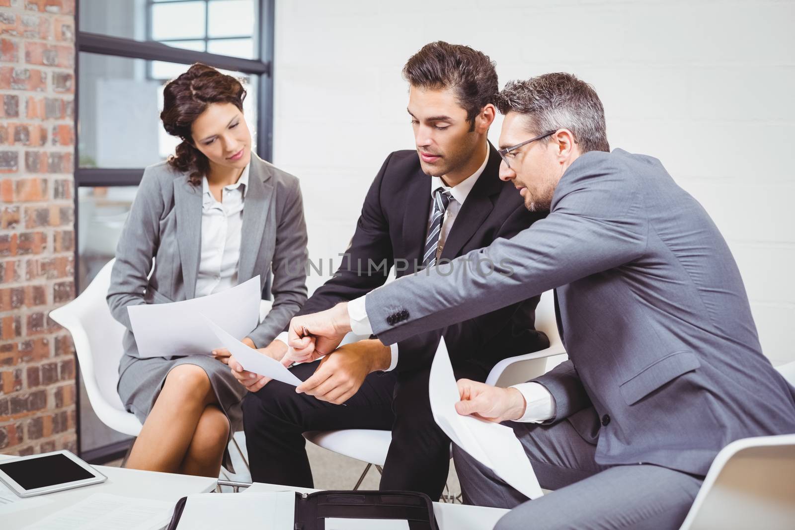 Business people holding documents while discussing at office