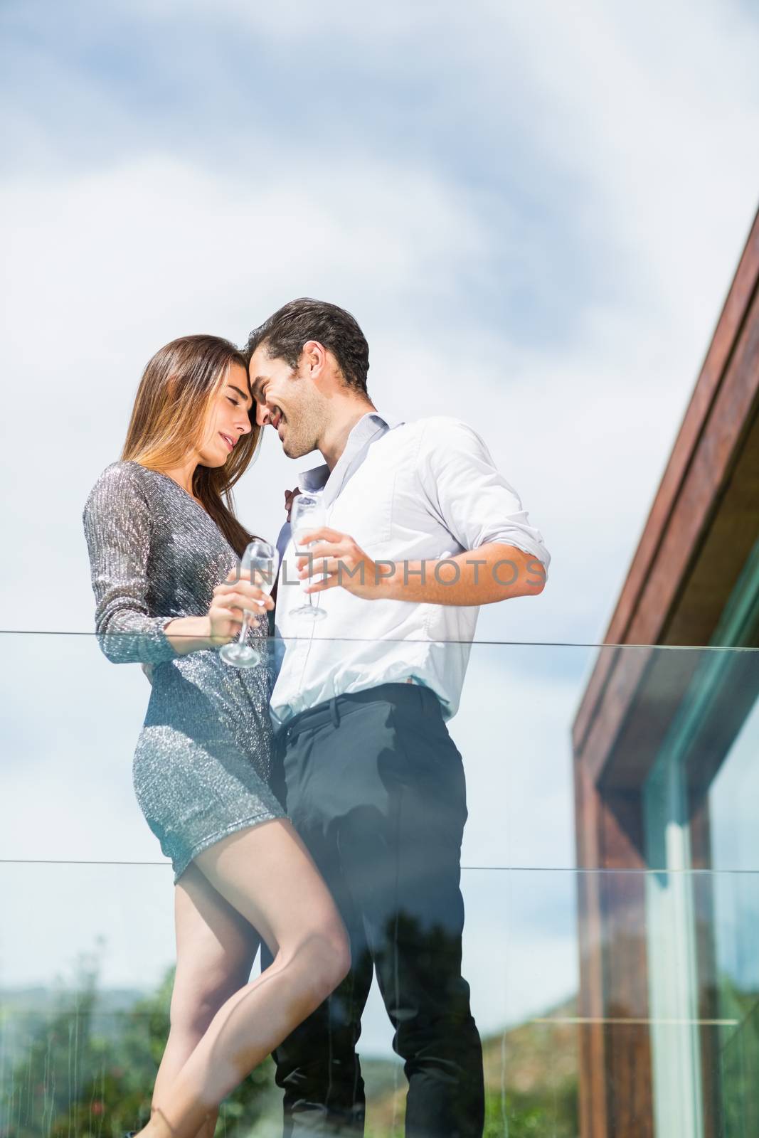 Romantic couple with champagne at balcony in resort by Wavebreakmedia