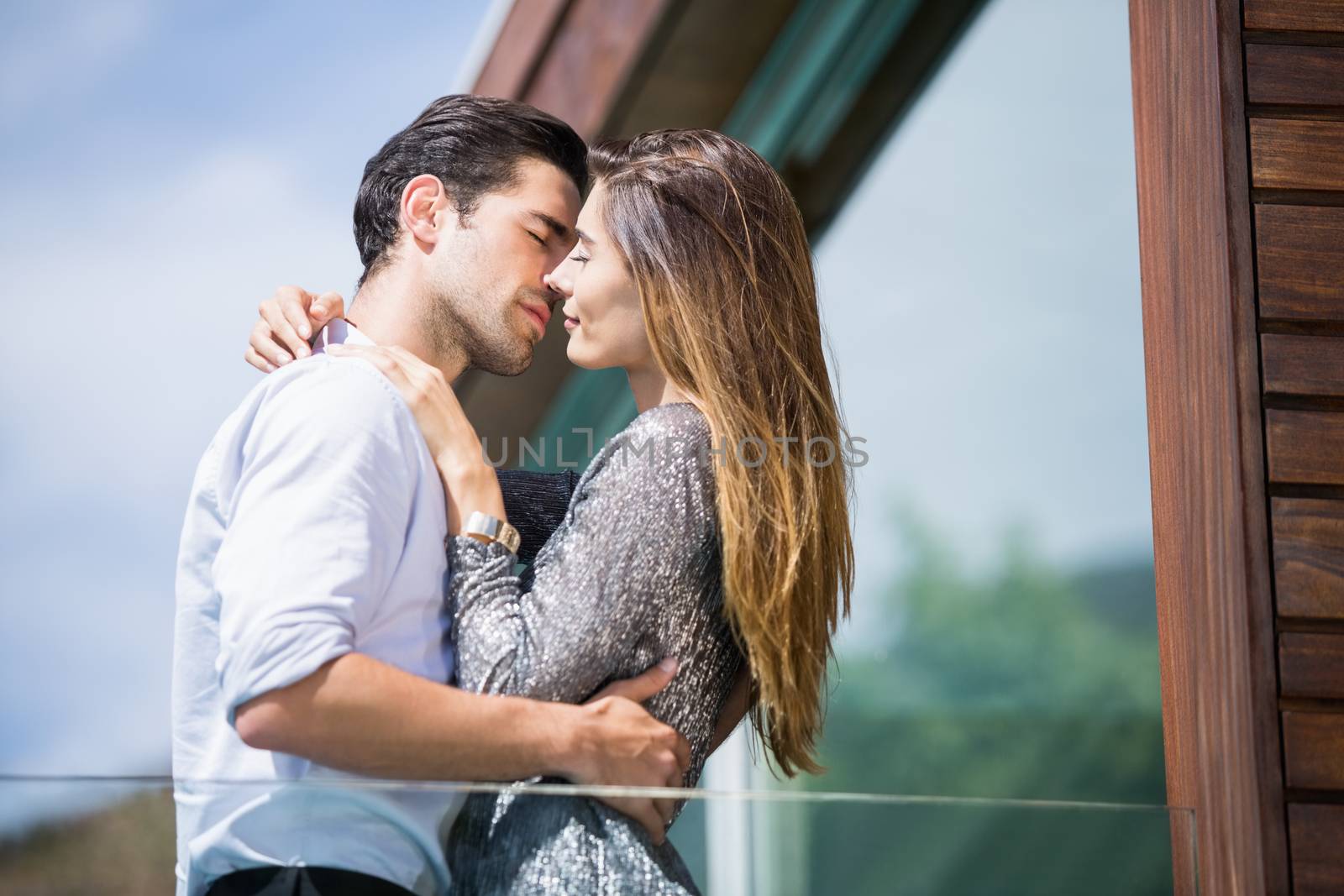 Low angle view of romantic young couple kissing in balcony at resort