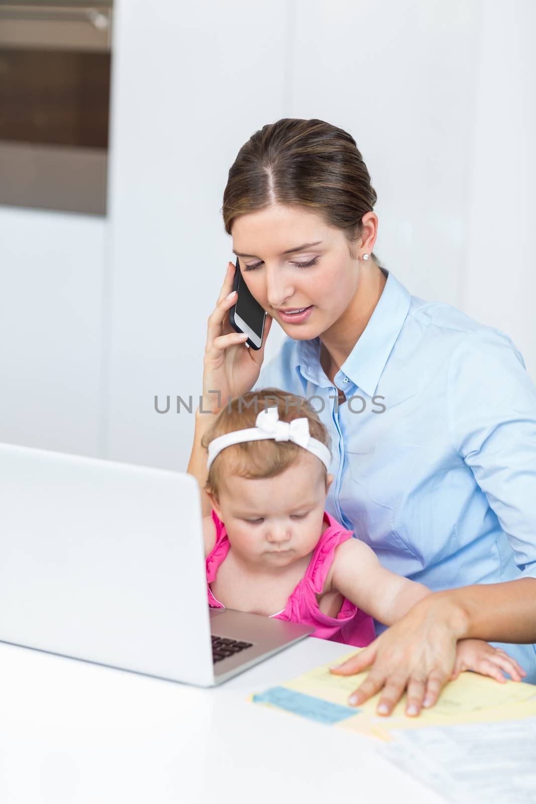 Woman talking on mobile phone sitting with baby girl by Wavebreakmedia