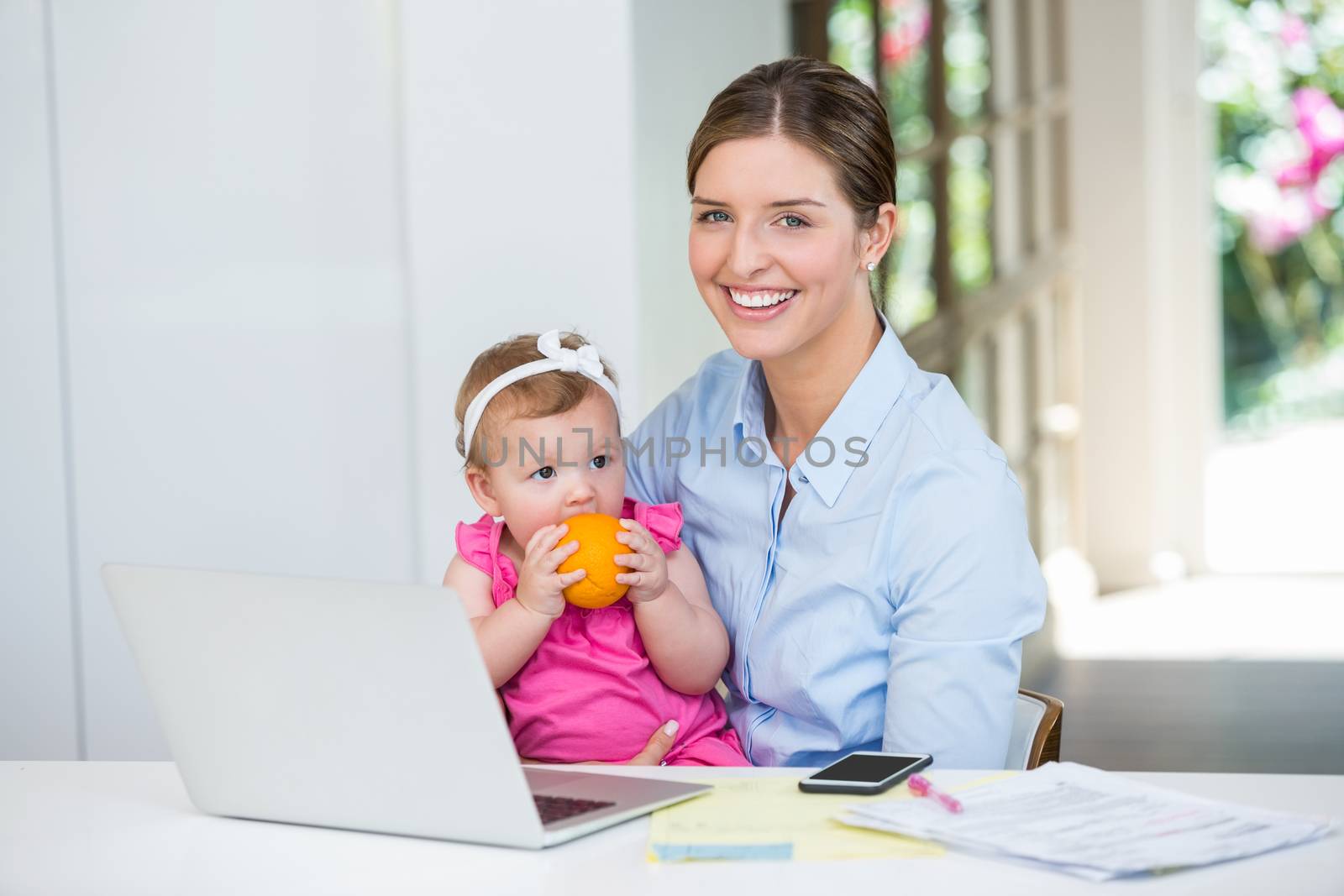 Happy woman sitting with baby by table at home