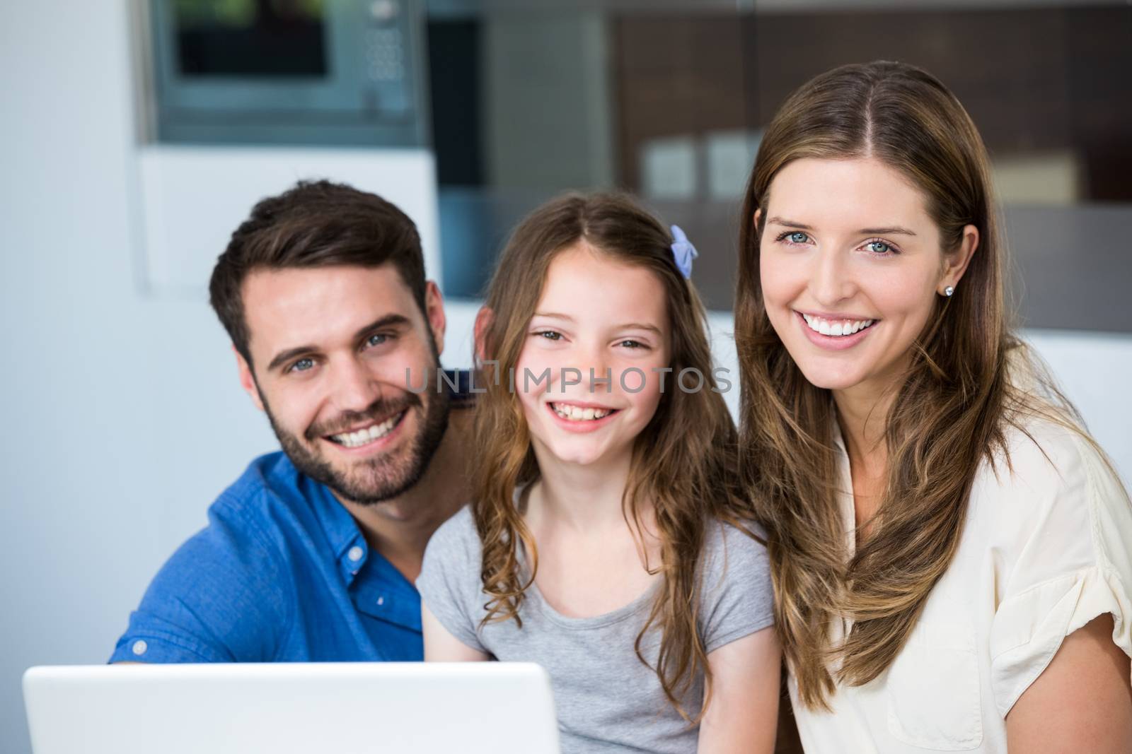Portrait of smiling family with laptop at home 