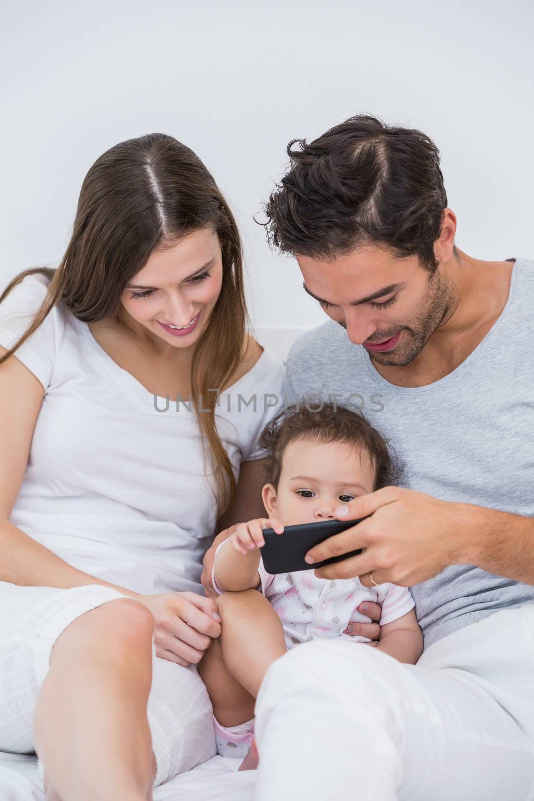 Happy couple enjoying with baby on bed at home 