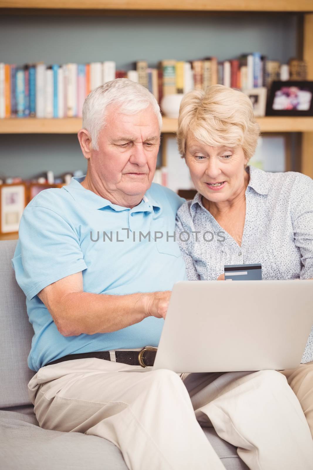 High angle view of senior couple using laptop while sitting on sofa at home
