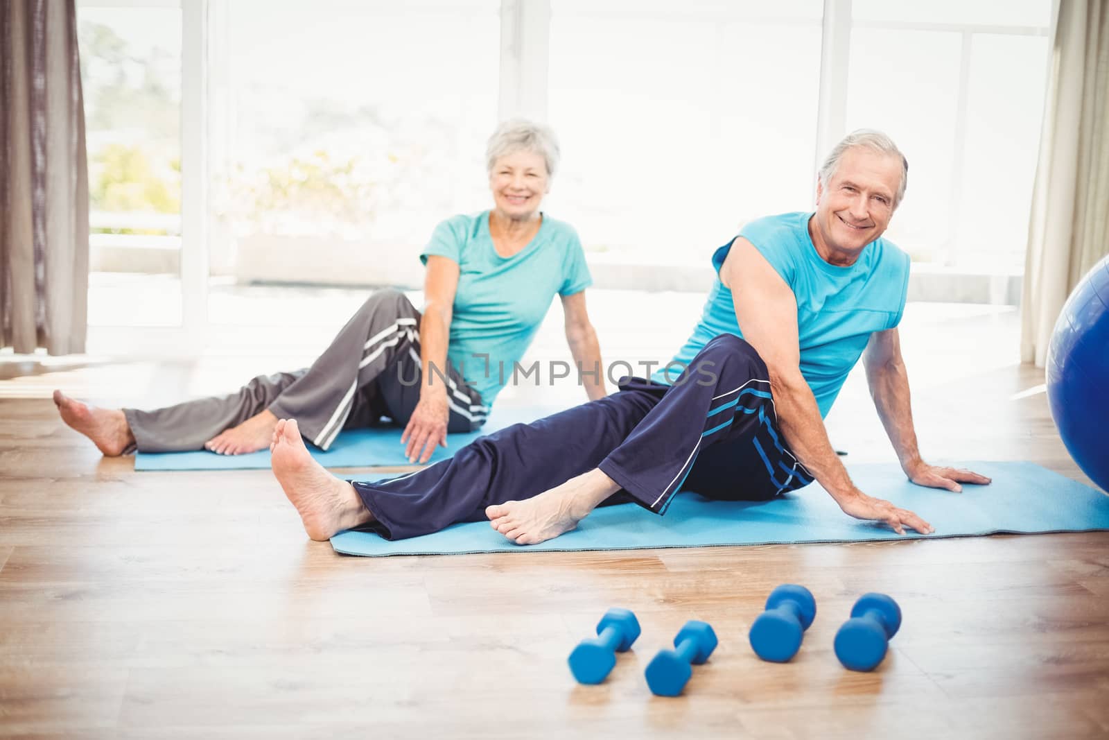 Portrait of smiling senior couple performing yoga at home