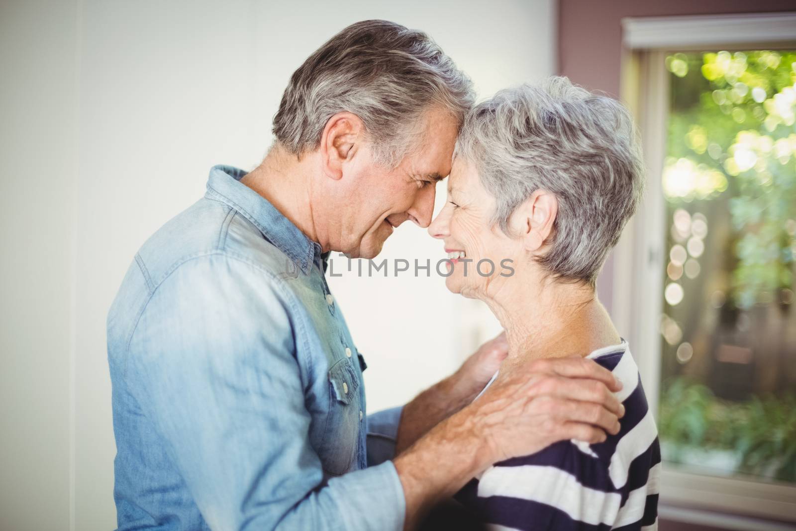 Romantic senior husband embracing wife at home