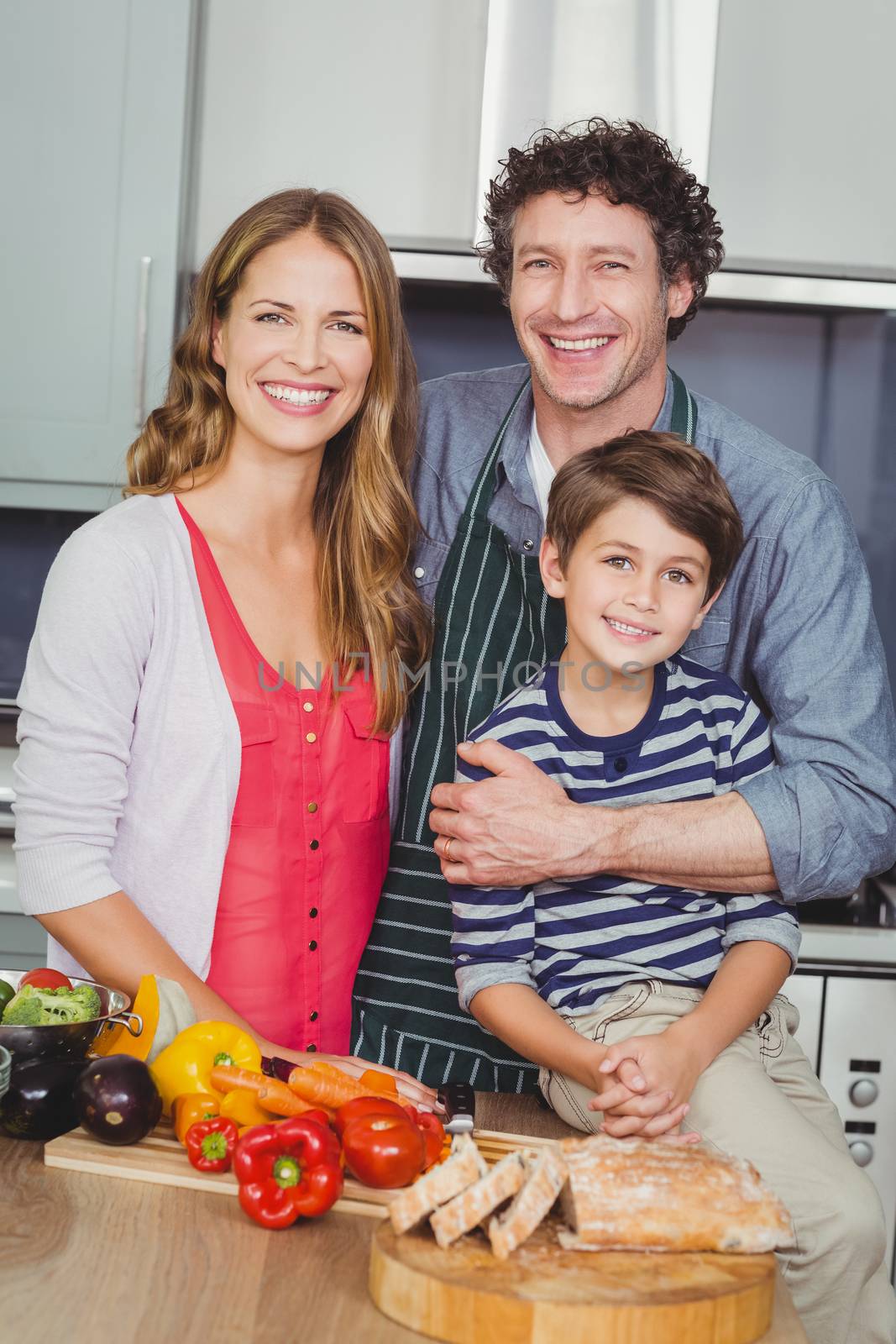Portrait of smiling parents with son in kitchen at home