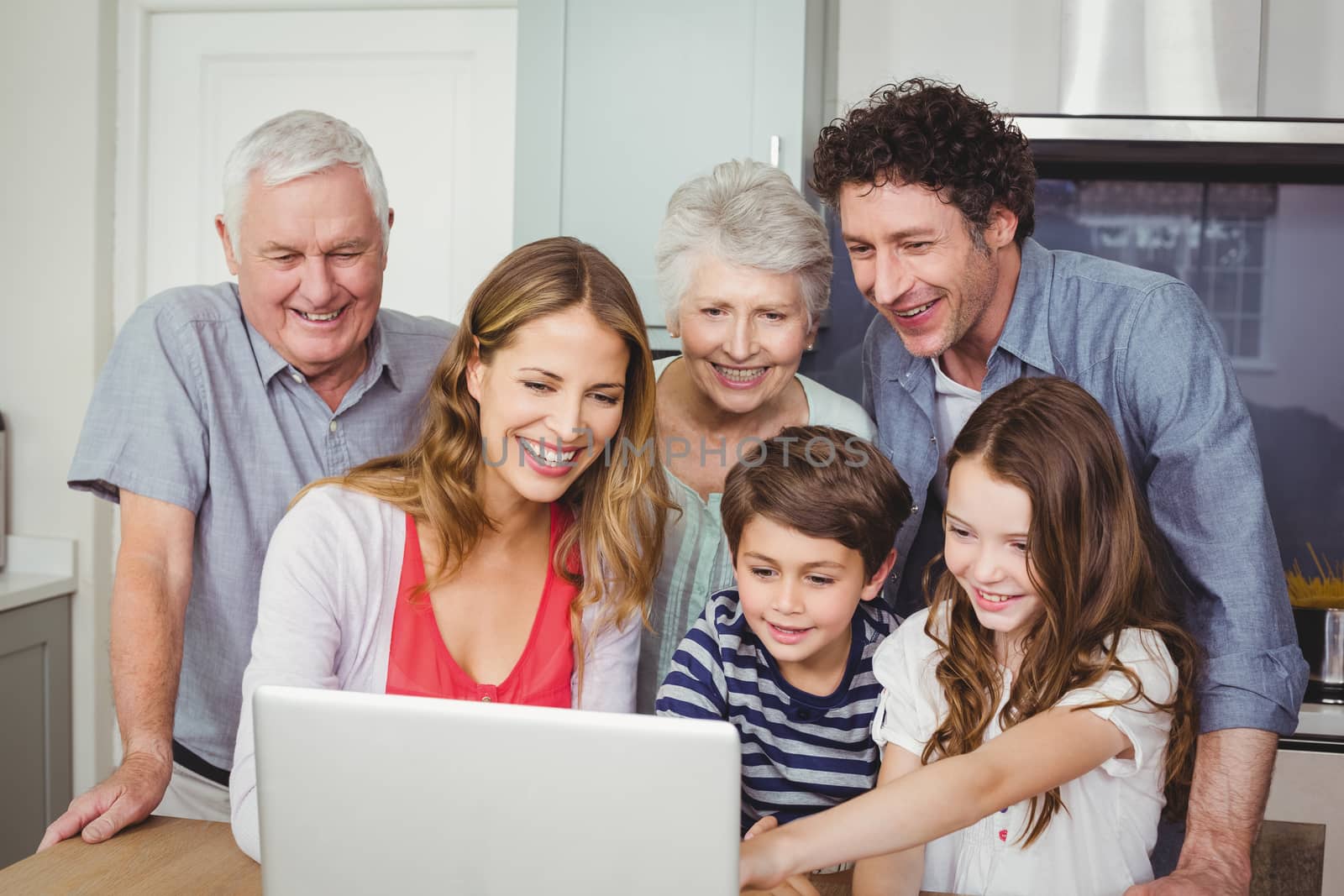 Smiling happy family using laptop in kitchen at home