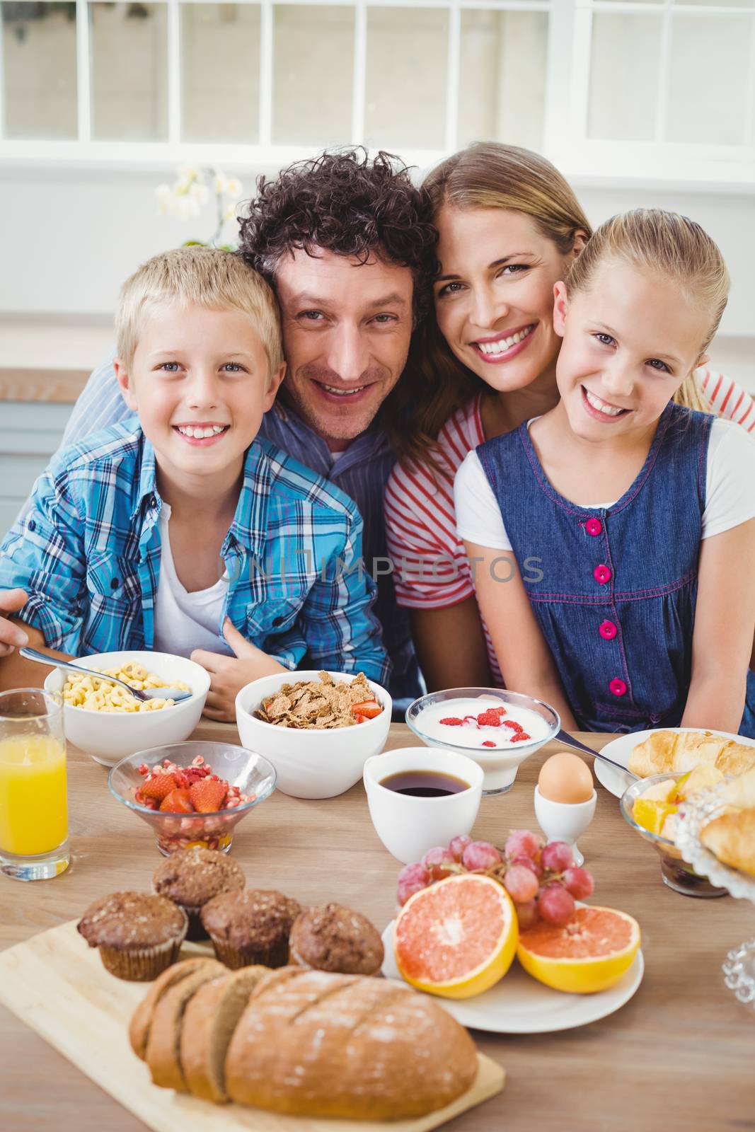 Portrait of family smiling while having breakfast at table in house