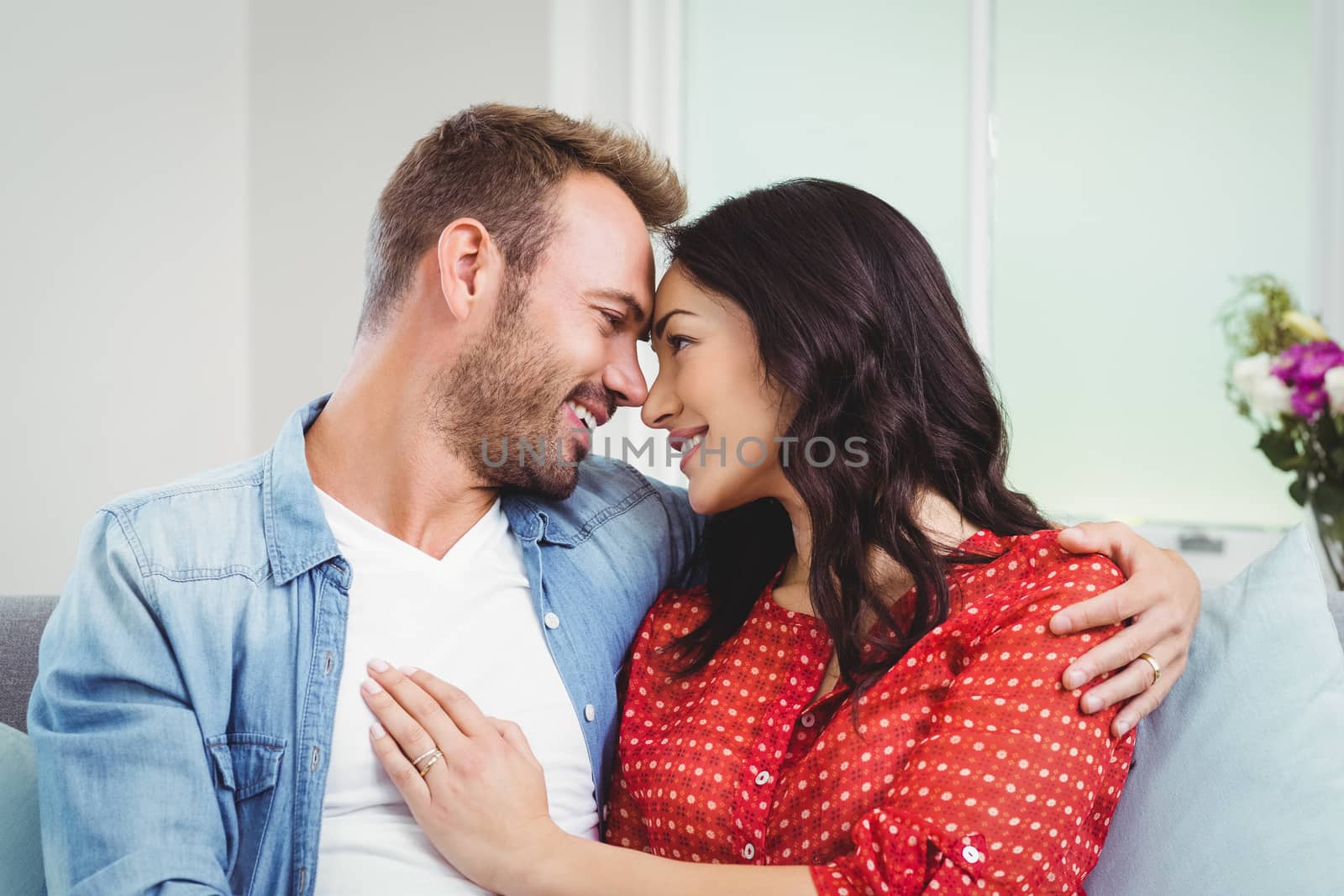 Romantic couple sitting on sofa at home by Wavebreakmedia