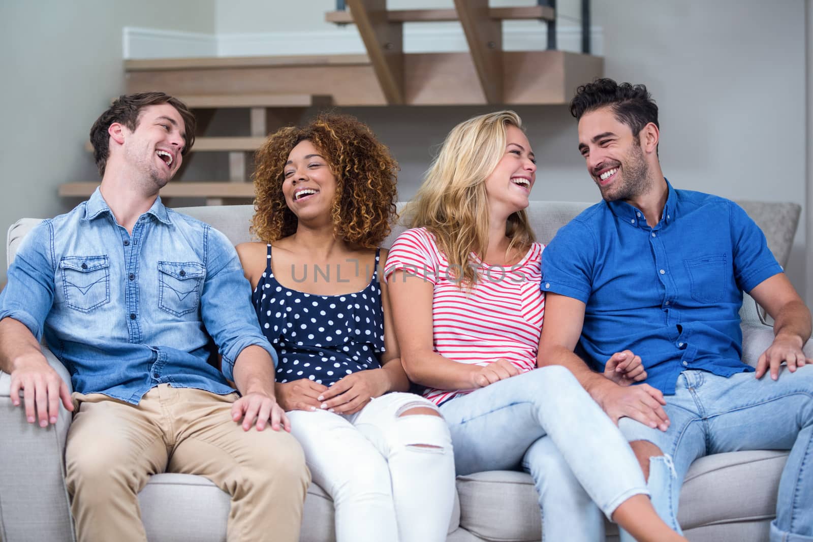 Cheerful young friends sitting on sofa at home