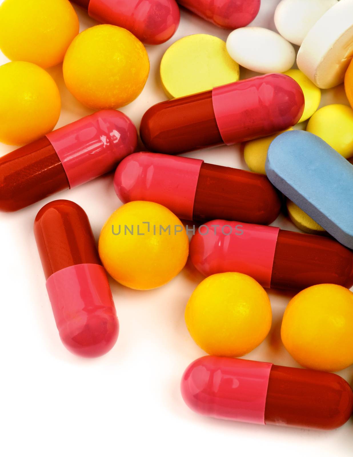 Heap of Various Pink, Red and Yellow Vitamin Pills closeup on White background