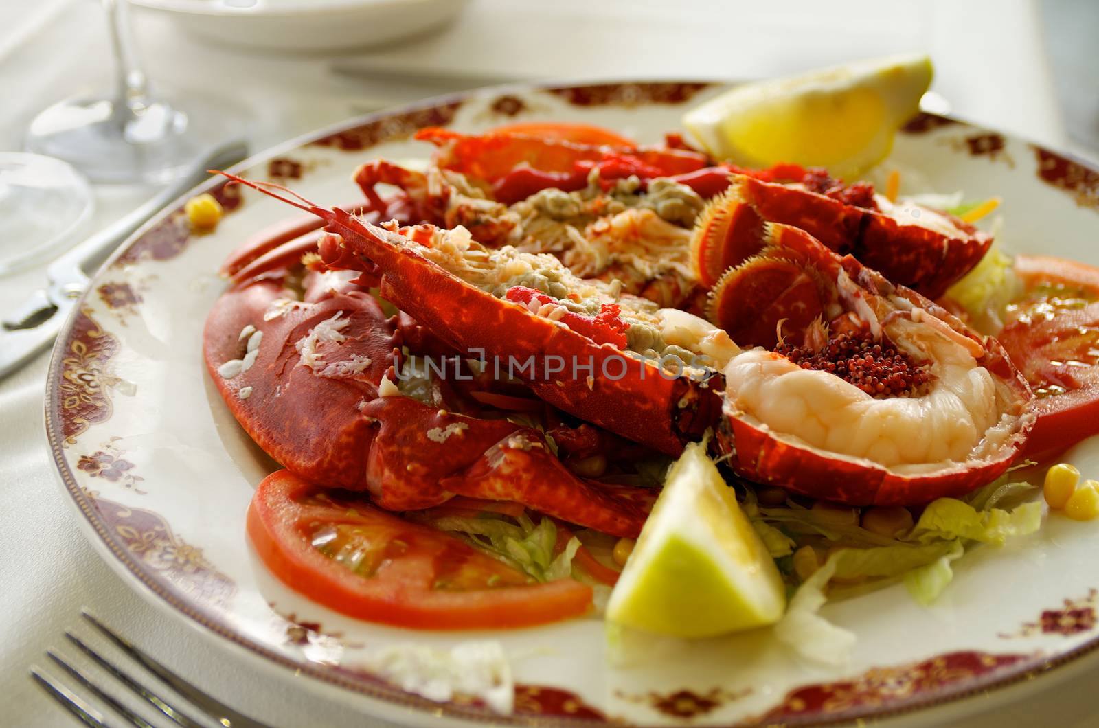 Gourmet Grilled Lobster with Vegetables Serving on Restaurant Table with Silver Fork closeup. Focus on Lobster Meat