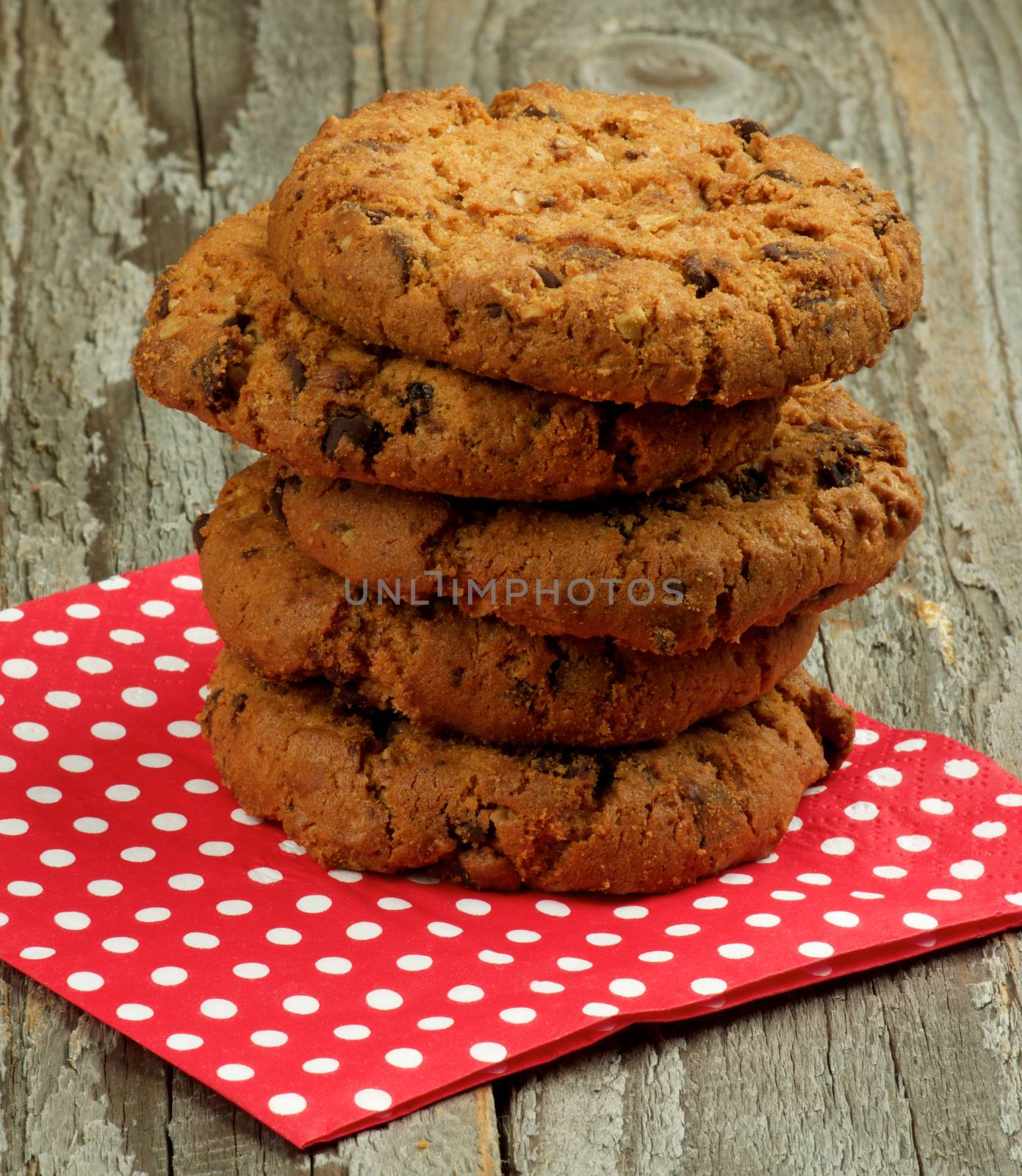 Stack of Chocolate Chip Cookies with Pieces of Nuts on Red Polka Dot Napkin closeup on Wooden background