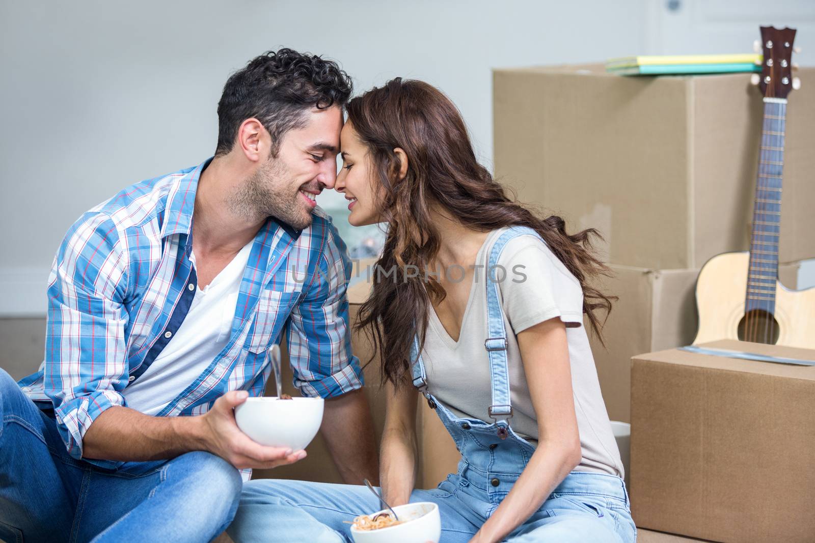 Romantic couple having noodles while sitting in new house