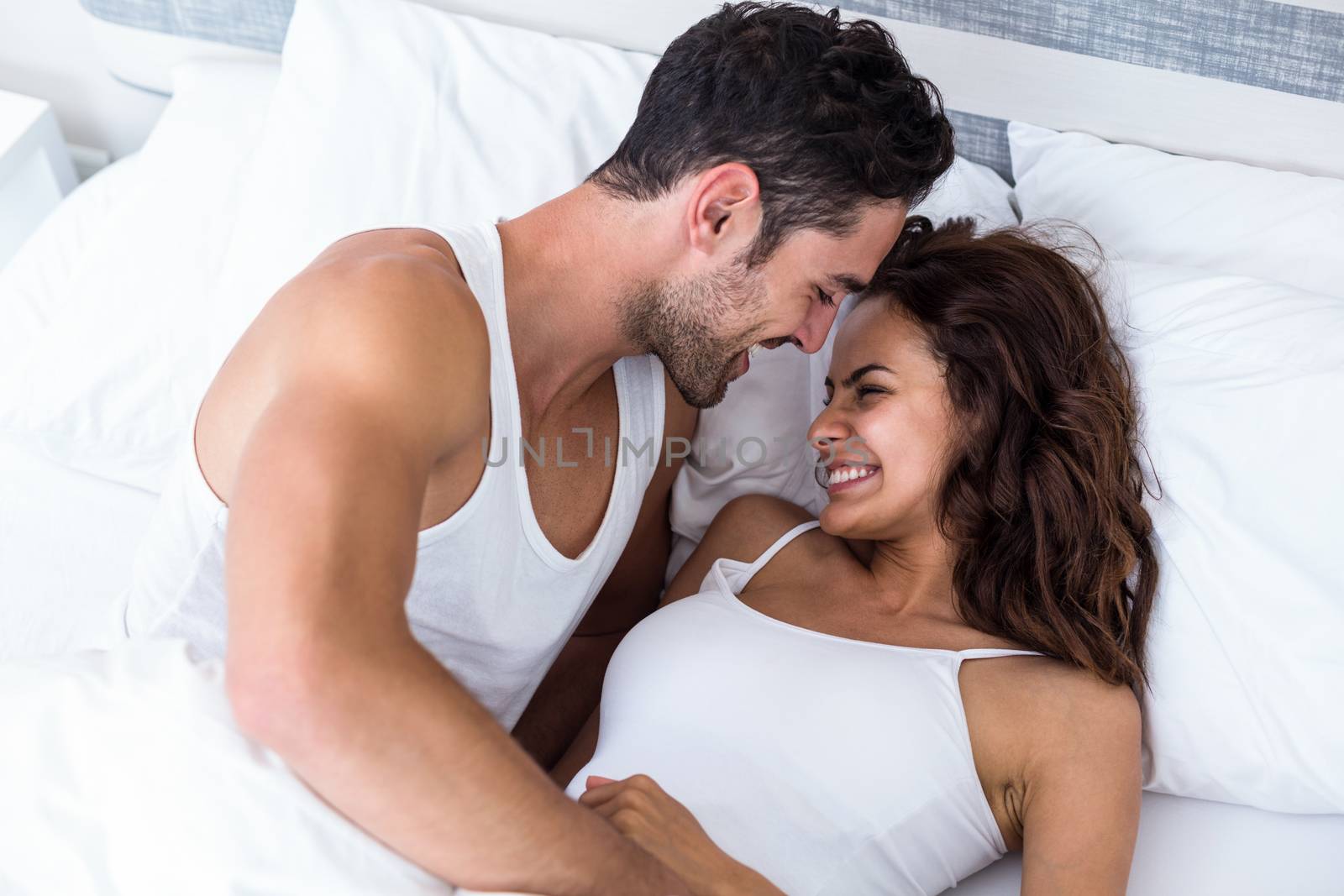 Smiling romantic couple relaxing on bed at home