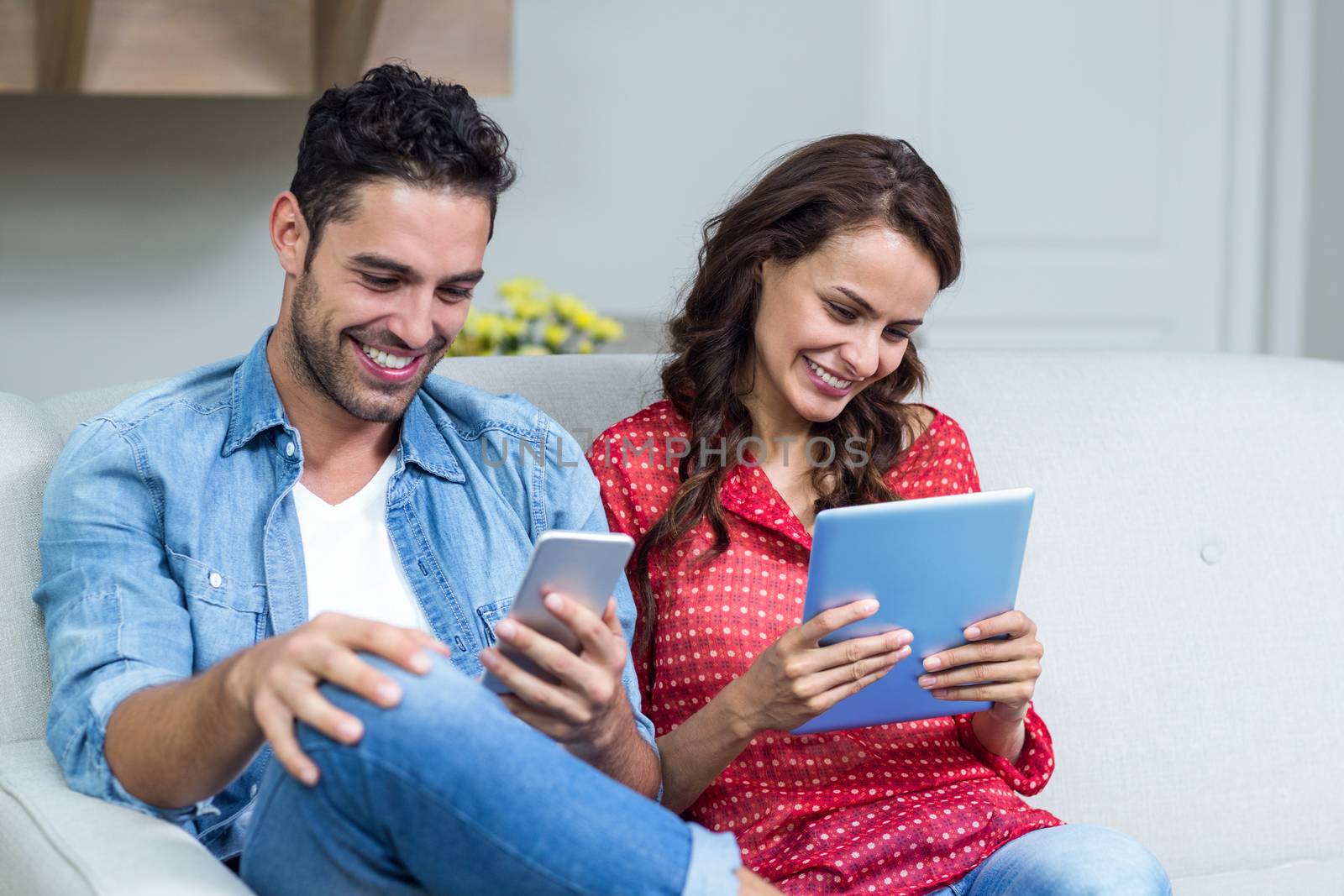 Smiling couple using technology  by Wavebreakmedia