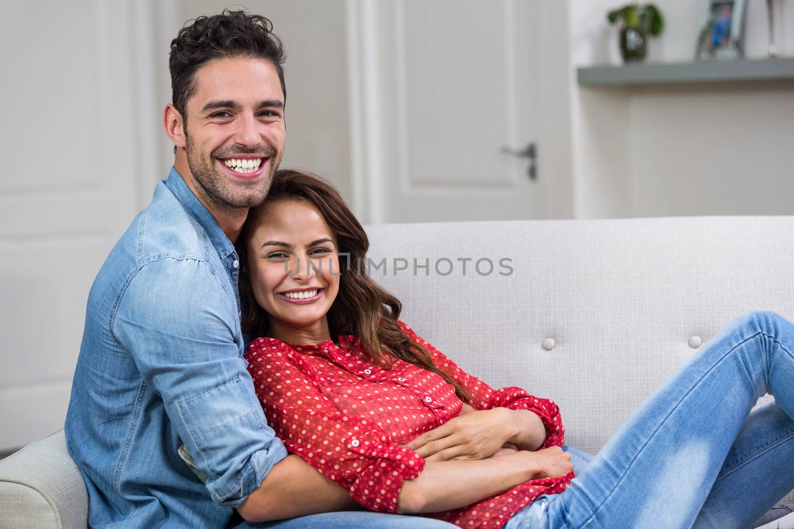 Portrait of romantic couple hugging on sofa by Wavebreakmedia