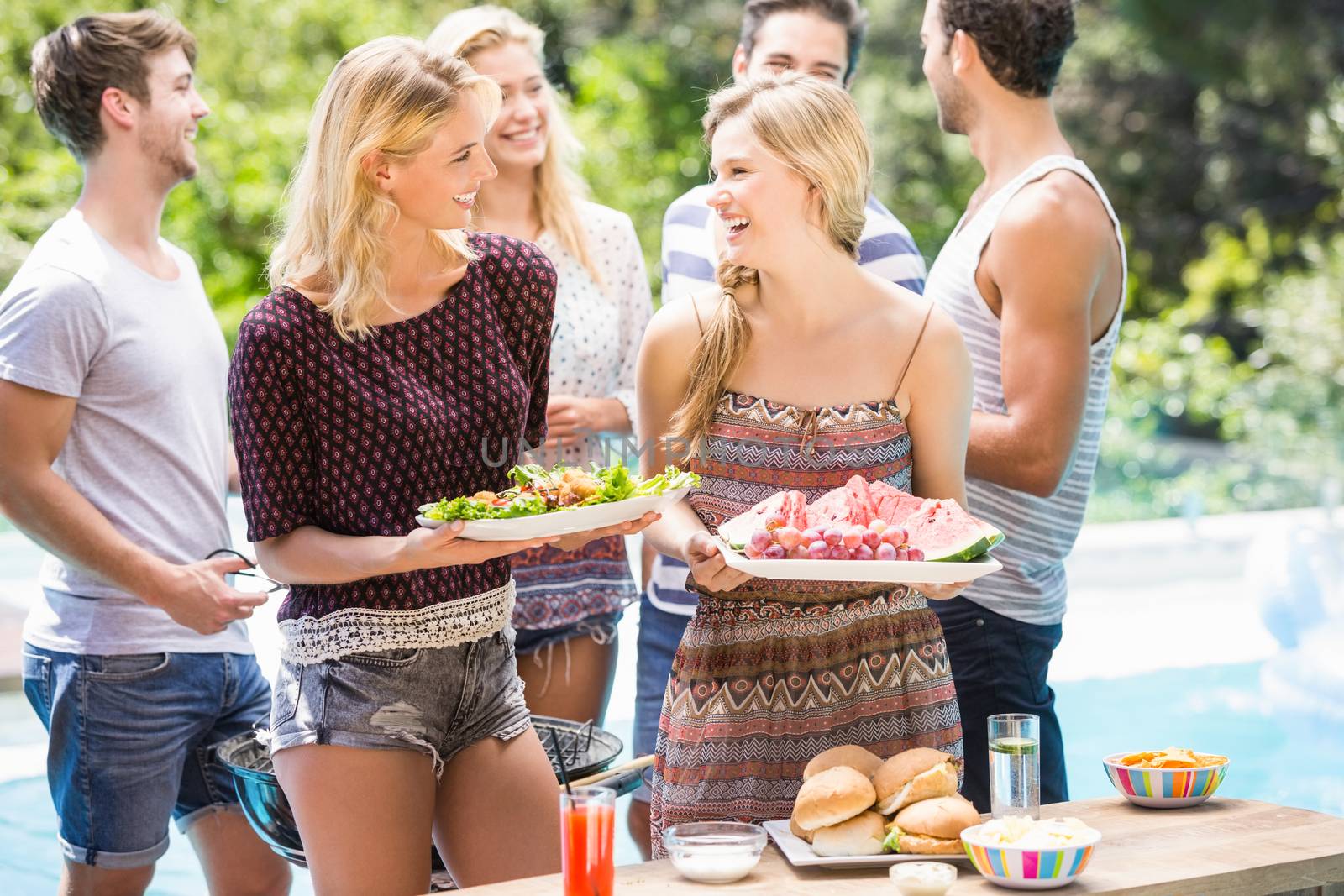 Friends preparing for outdoors barbecue party by Wavebreakmedia