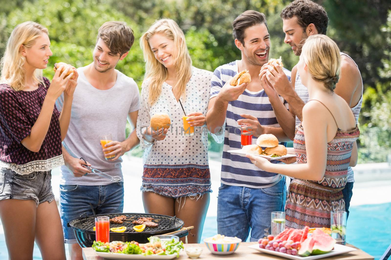 Group of friends having hamburgers and juice by Wavebreakmedia